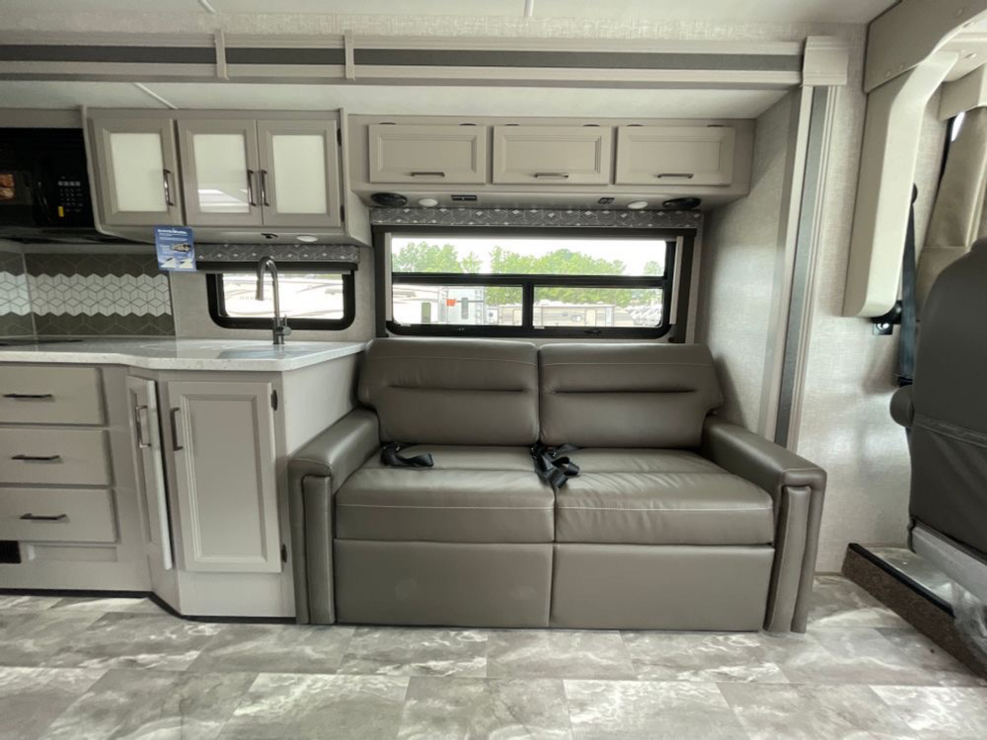 Spacious RV rental with a modern kitchenette, comfortable sofa, and large windows. Perfect for your next road trip!. Ford Windsport 2023