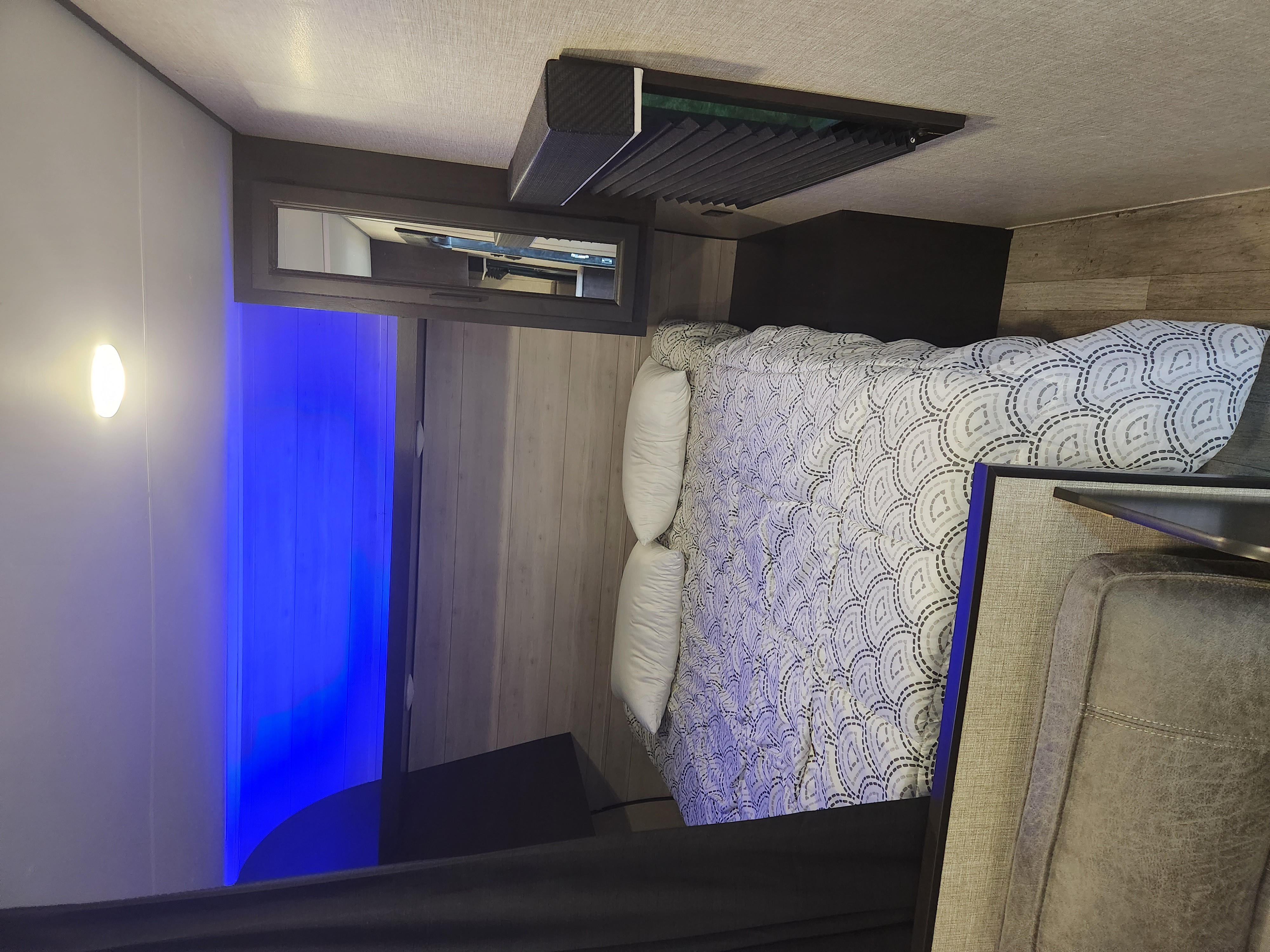 Vibrant blue LED lighting illuminates this cozy RV rental bedroom with patterned bedding & overhead storage.. Jayco Jay Flight SLX Rocky Mountain Edition 2022
