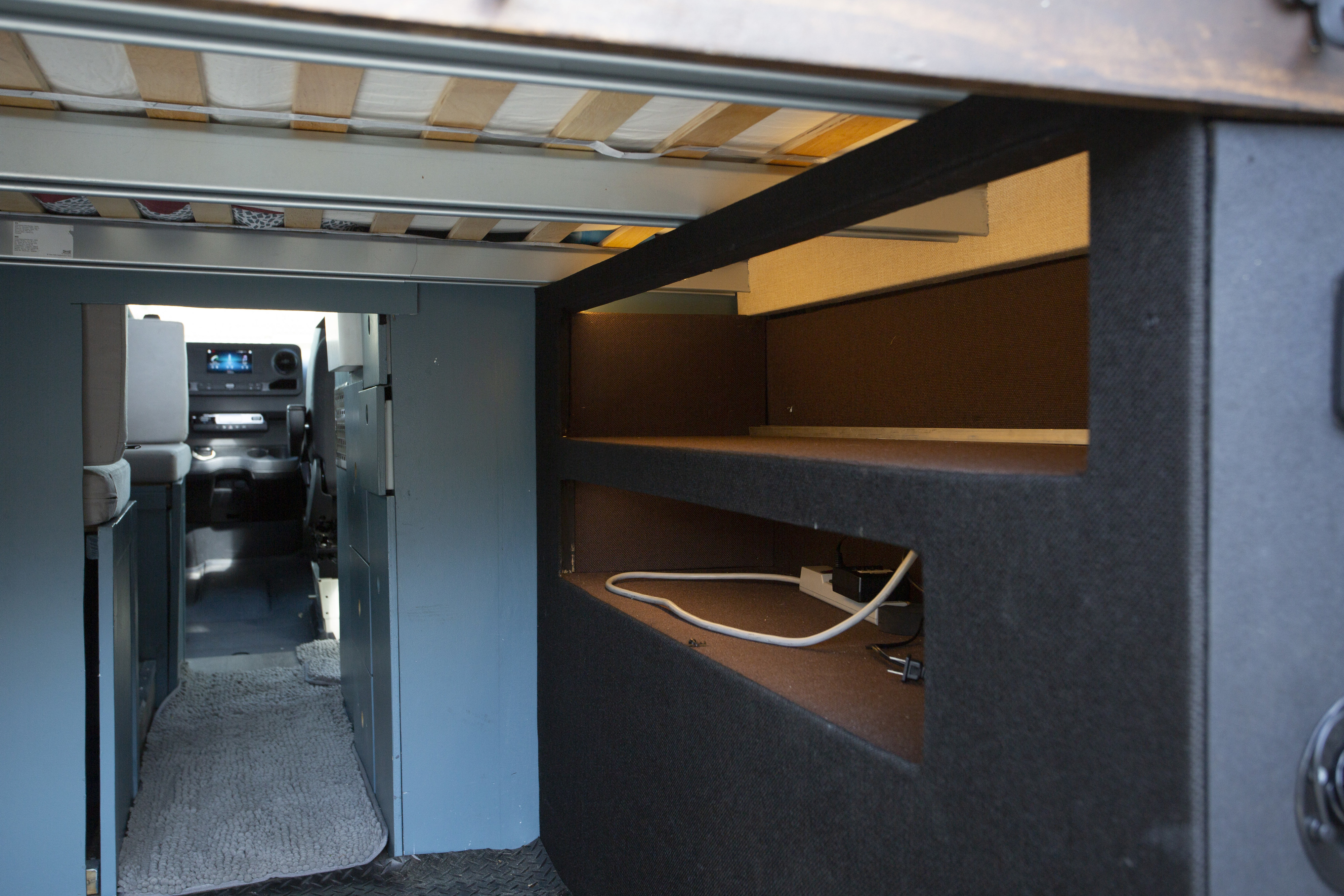 Explore this RV rental's interior: a raised bed, built-in storage with power outlets, and a clear view into the driver's cabin.. Mercedes 2500 2022