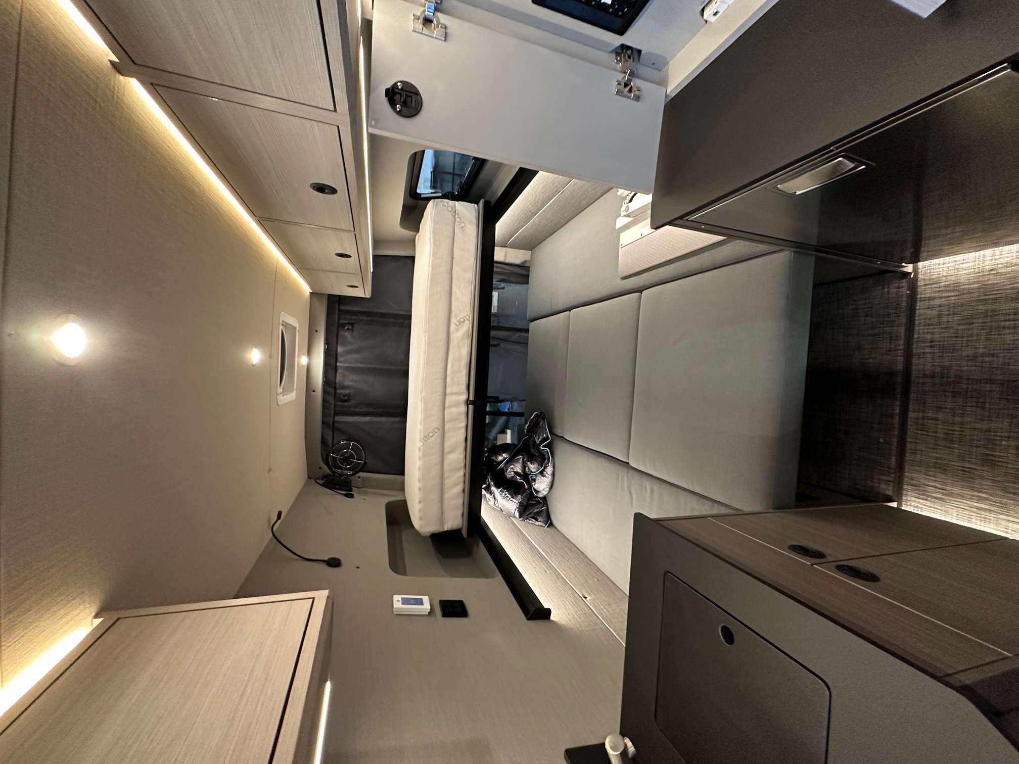 Modern RV rental interior, showcasing a versatile layout with a stowed bed, bench seating, and ambient strip lighting.. Mercedes Sprinter 2020