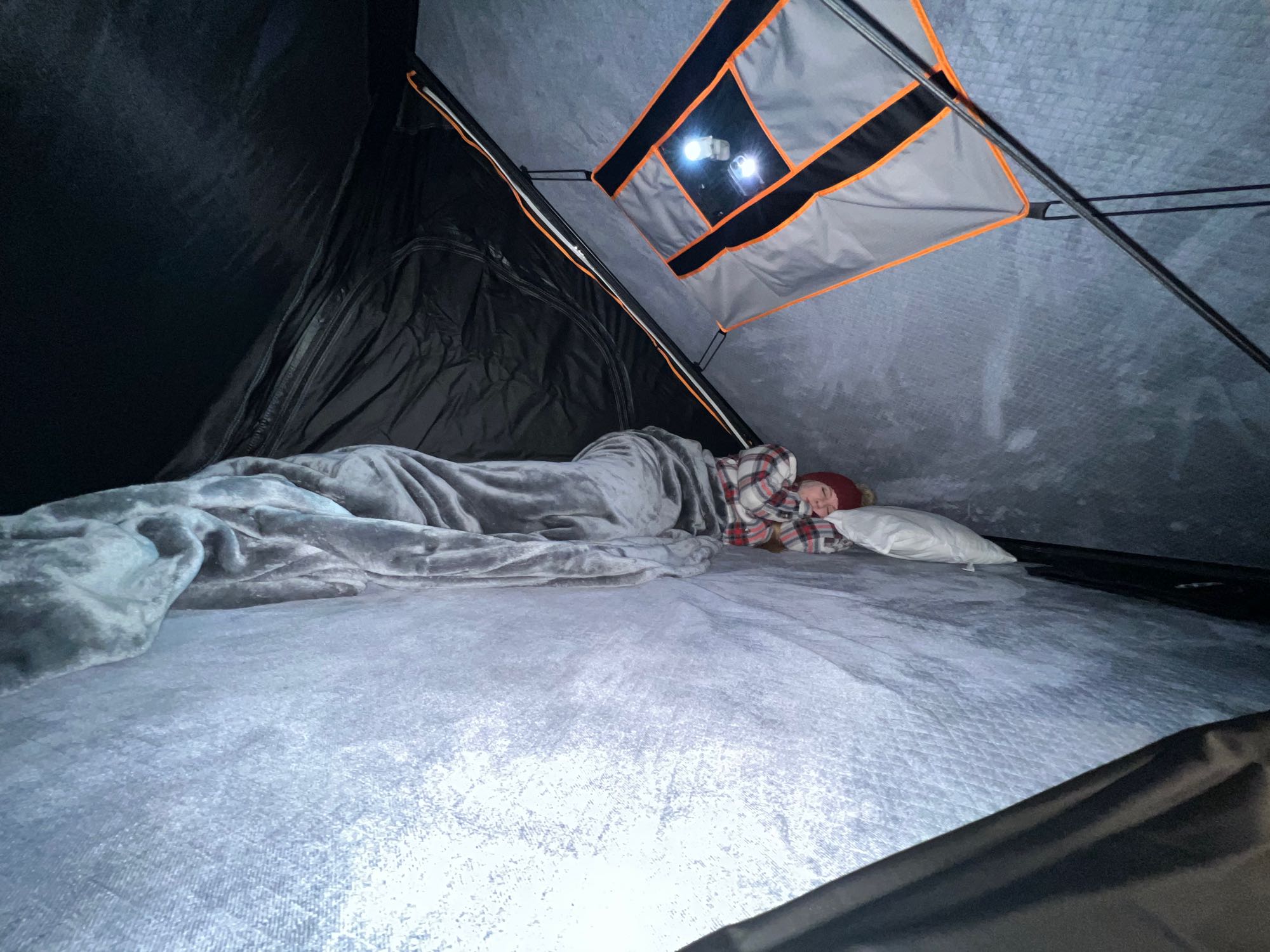 Inside a cozy RV rental: a person sleeps soundly on a plush bed under a blanket, with interior lights glowing.. Honda Element 2007