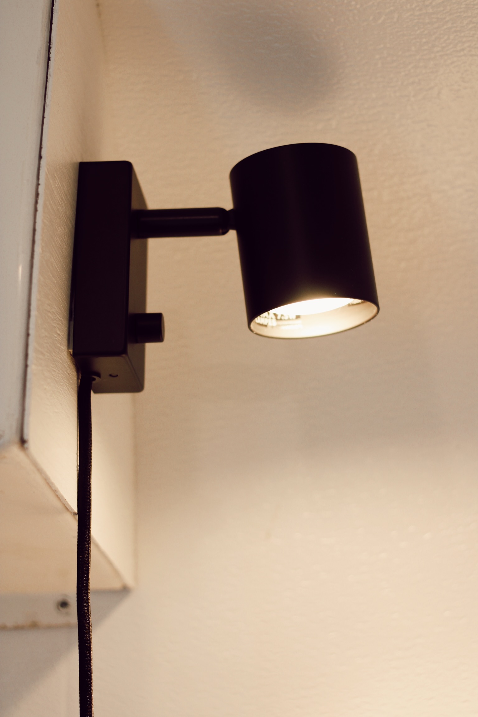 Compact black wall lamp providing warm light in an RV rental interior. Perfect for cozy reading nooks.. Scamp Scamp Trailer 2005