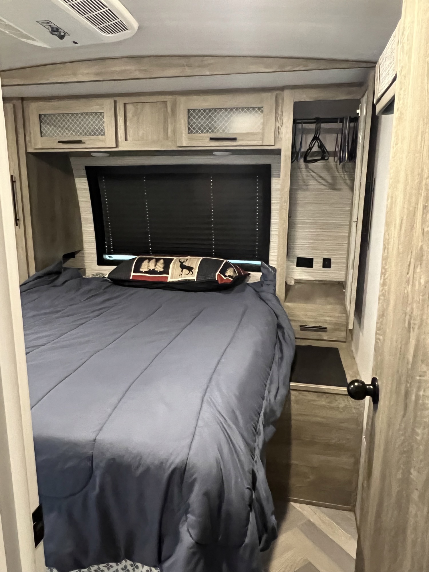Inside an RV rental: a compact bedroom with a blue bed, modern cabinets, built-in storage, and AC unit for comfort.. Forest River Salem Hemisphere 2022