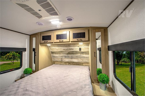 RV rental bedroom featuring a comfortable bed, ample overhead storage, scenic windows, and an AC unit for comfort.. Heartland RVs Sundance Ultra Lite 2022