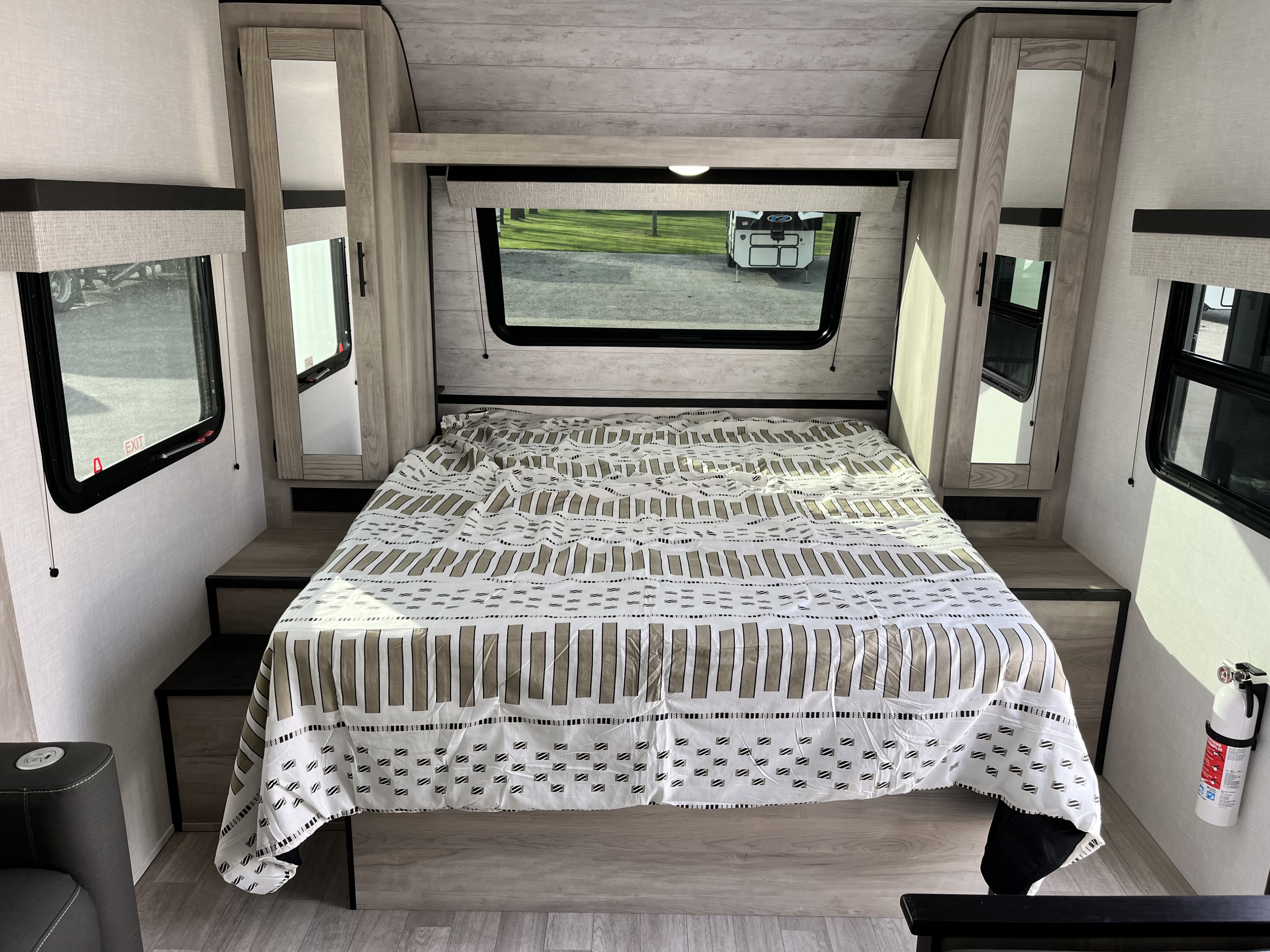 Inside this RV rental's bedroom: a patterned bed, windows, built-in storage, and a wall-mounted fire extinguisher.. KZ Connect SE C211MKSE 2025