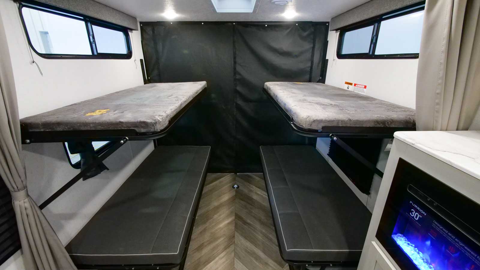 Explore this RV rental's versatile interior: two elevated bunk beds, lower seating, and a privacy partition for flexible space.. Forest River Wildwood FSX PLATINUM Toy Hauler 2022