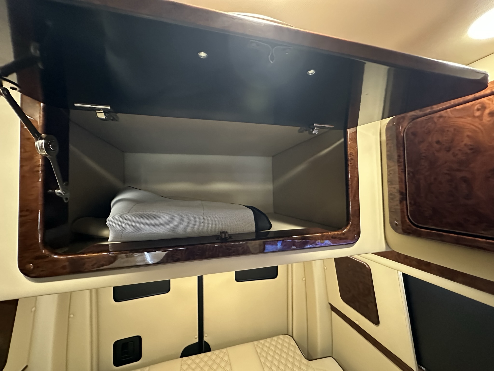 Luxury rv rental interior with an open overhead storage cabinet, showcasing polished wood and light upholstery.. American Patriot American Patriot Class B 2021
