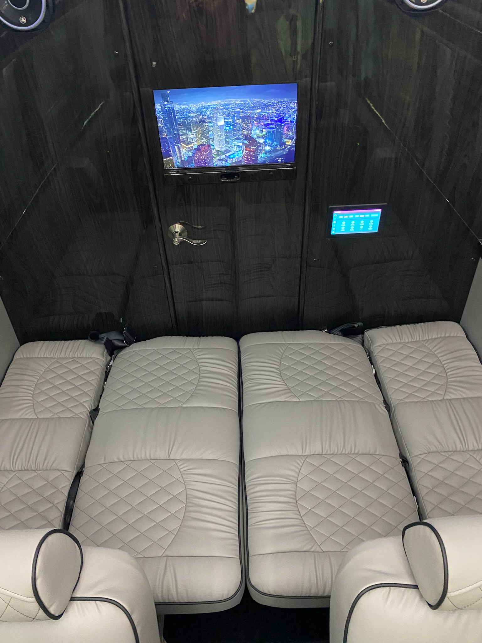 Luxury RV rental interior: spacious cabin with plush grey quilted beds, entertainment TV, and control panel. Ideal for travel.. Midwest Automotive Designs Ultimate Coach 2023