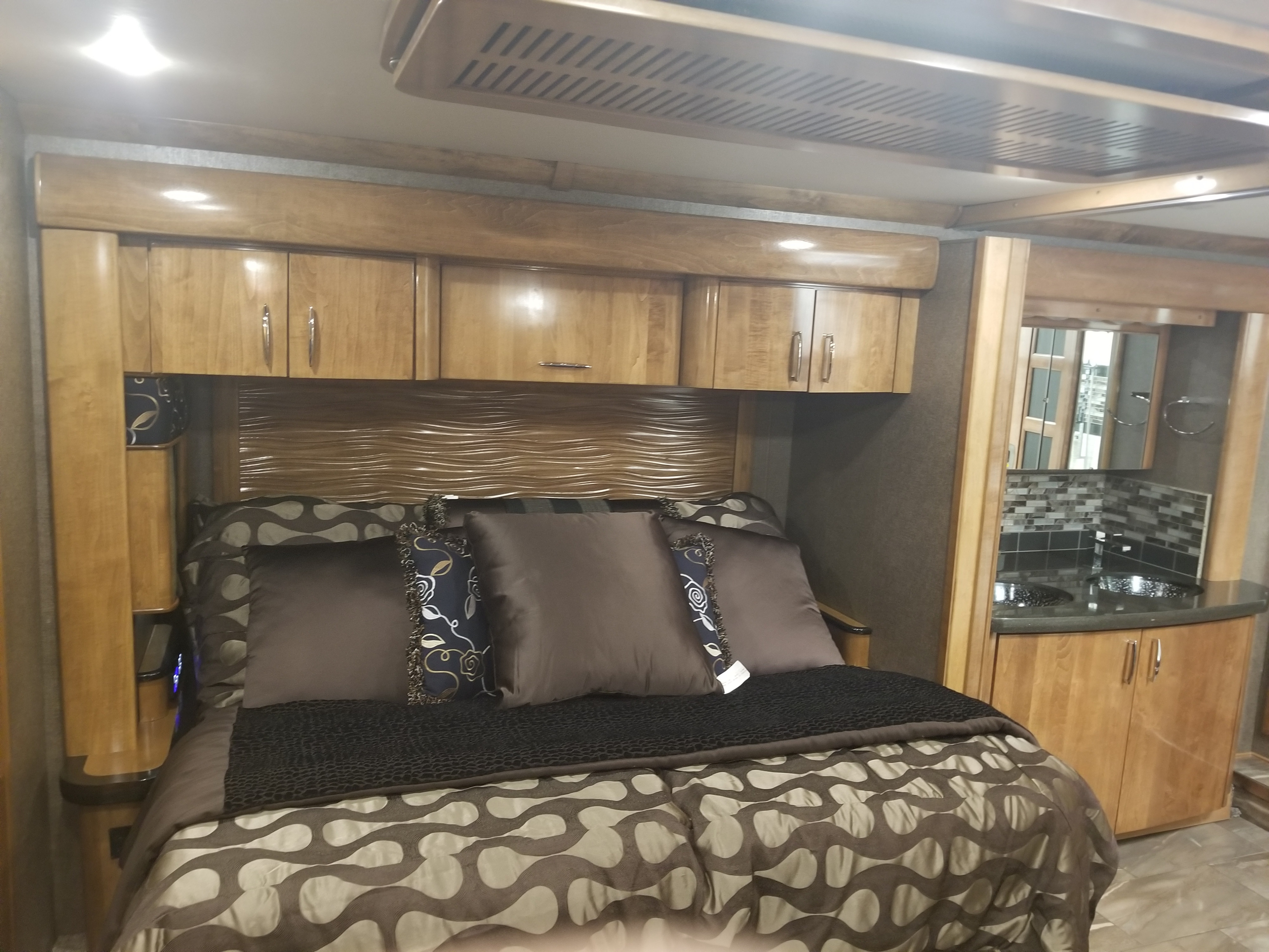 Experience comfort in this RV rental bedroom: a plush bed, sleek cabinetry, and a convenient vanity area.. American Coach American Eagle 2017