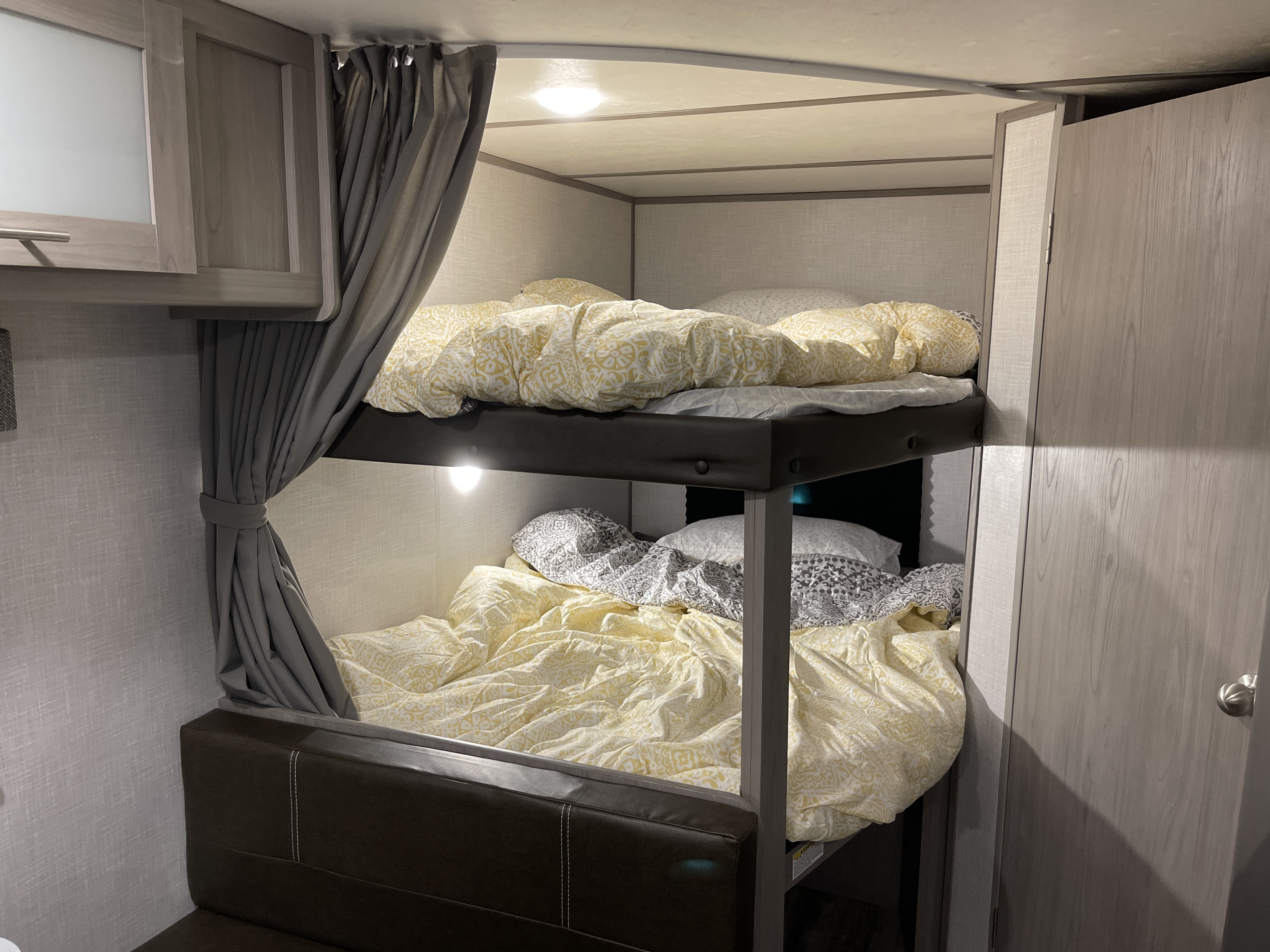 Cozy RV rental interior showing comfortable bunk beds with patterned bedding and privacy curtains.. Dutchmen Coleman Lantern LT 2022