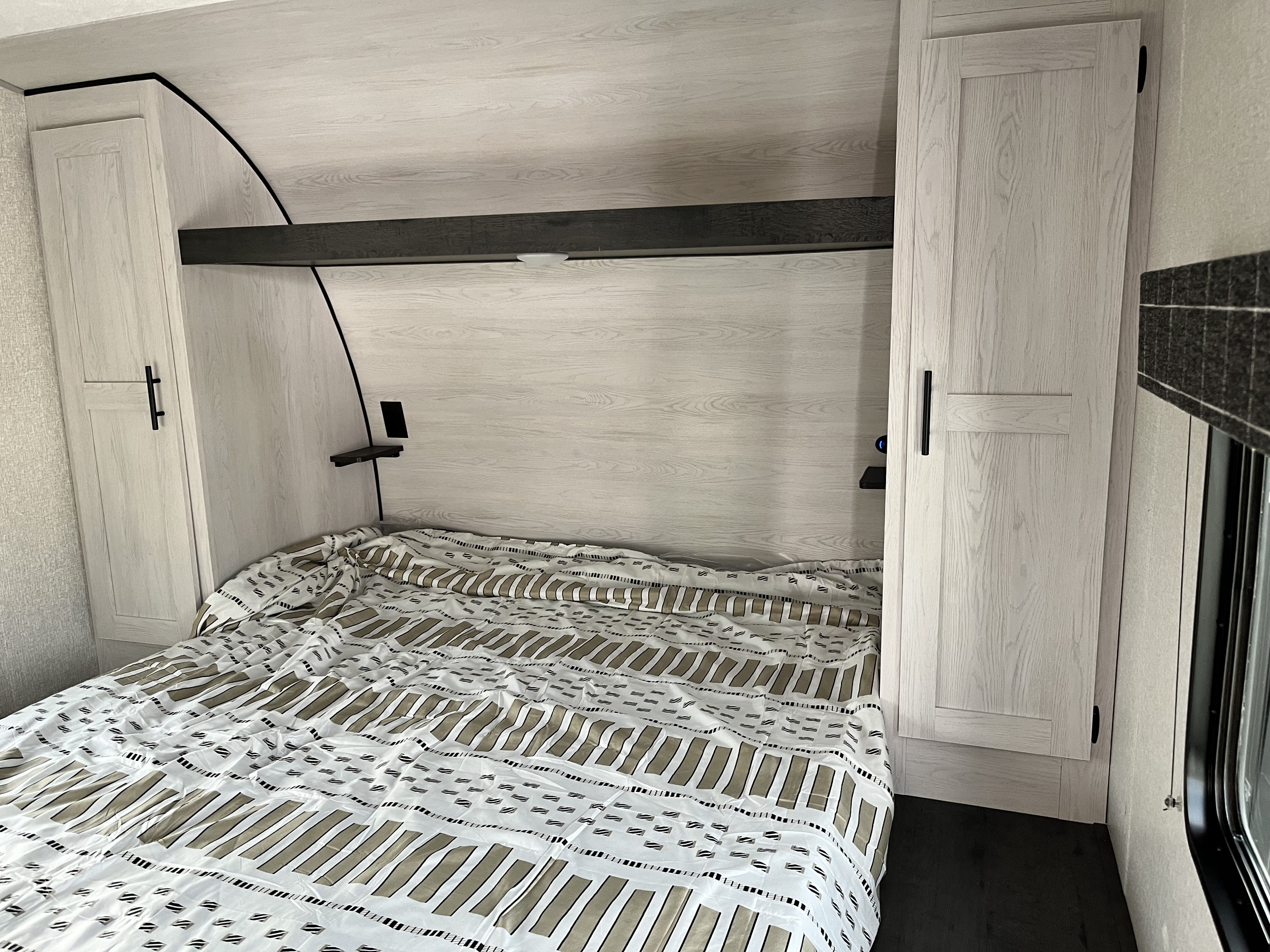 Cozy RV rental bedroom featuring a comfortable bed, light wood-grain cabinets, and an overhead shelf for essentials.. KZ Sportsmen SE 301BHKSE 2025