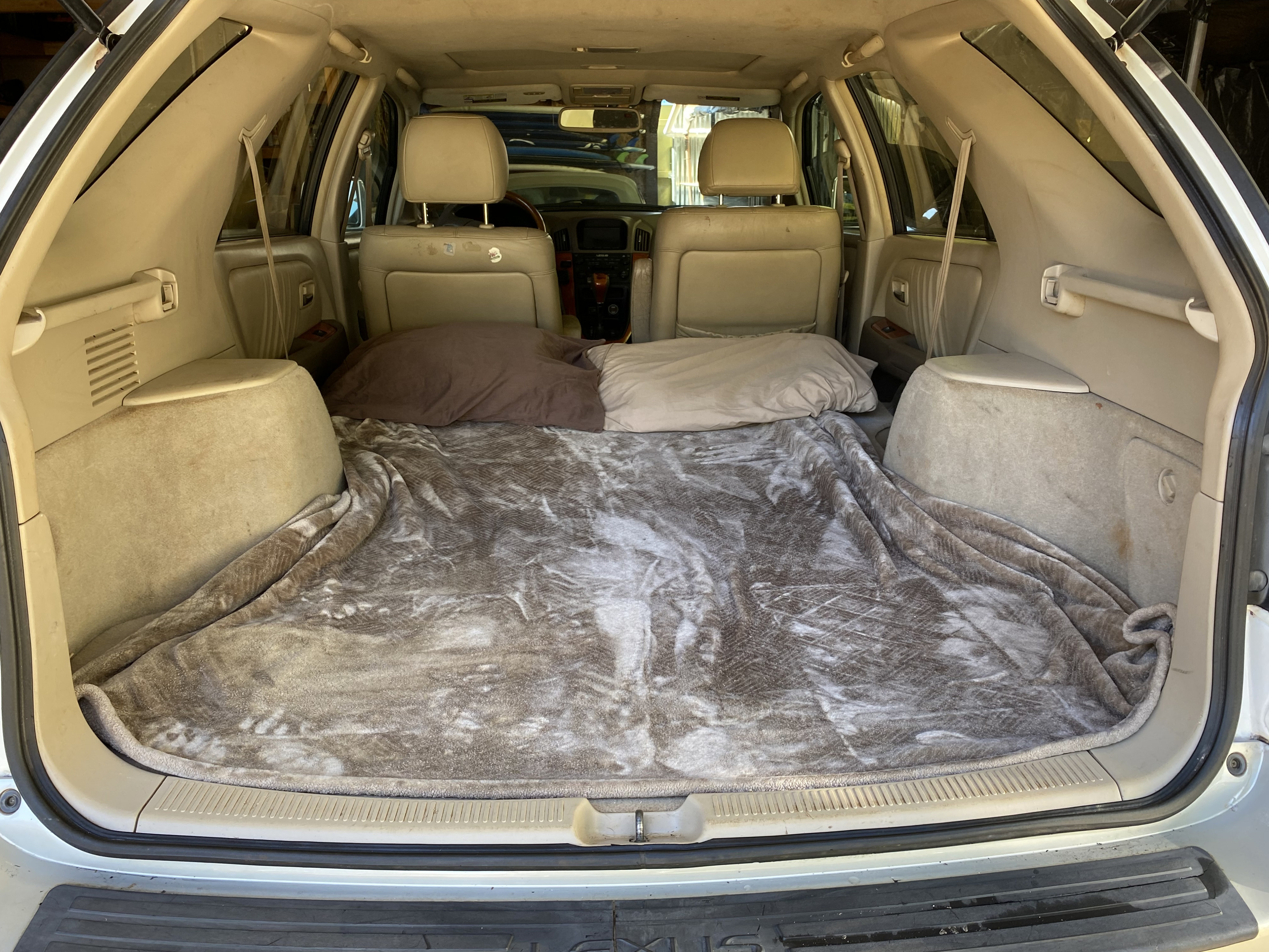SUV cargo area transformed into a cozy sleeping space with blankets & pillows. A budget-friendly RV rental alternative.. lexus RX300 2003