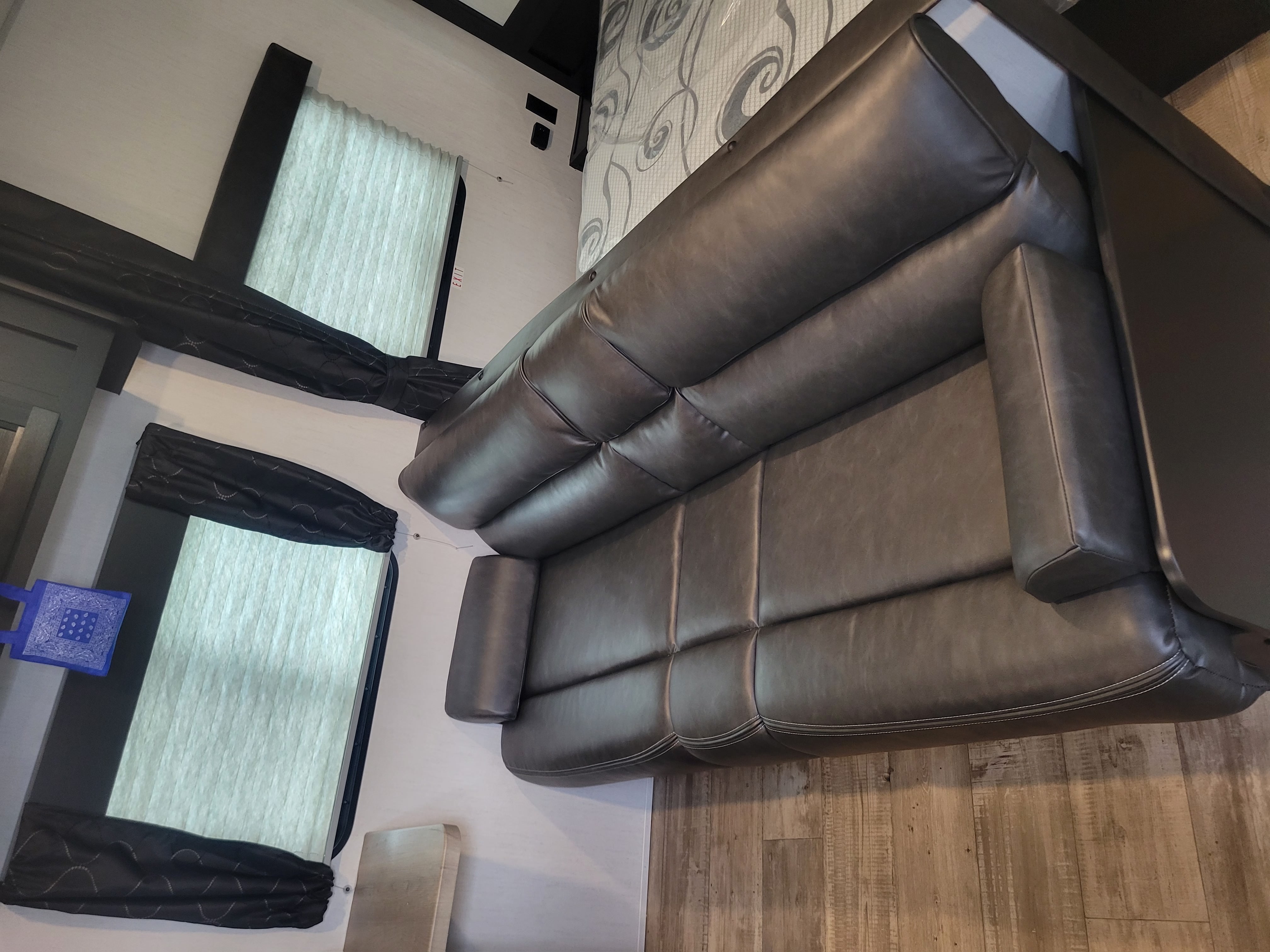 Cozy RV rental interior with a spacious dark grey sofa, wood flooring, and large windows.. Forest River Cherokee Grey Wolf Special Edition 2022