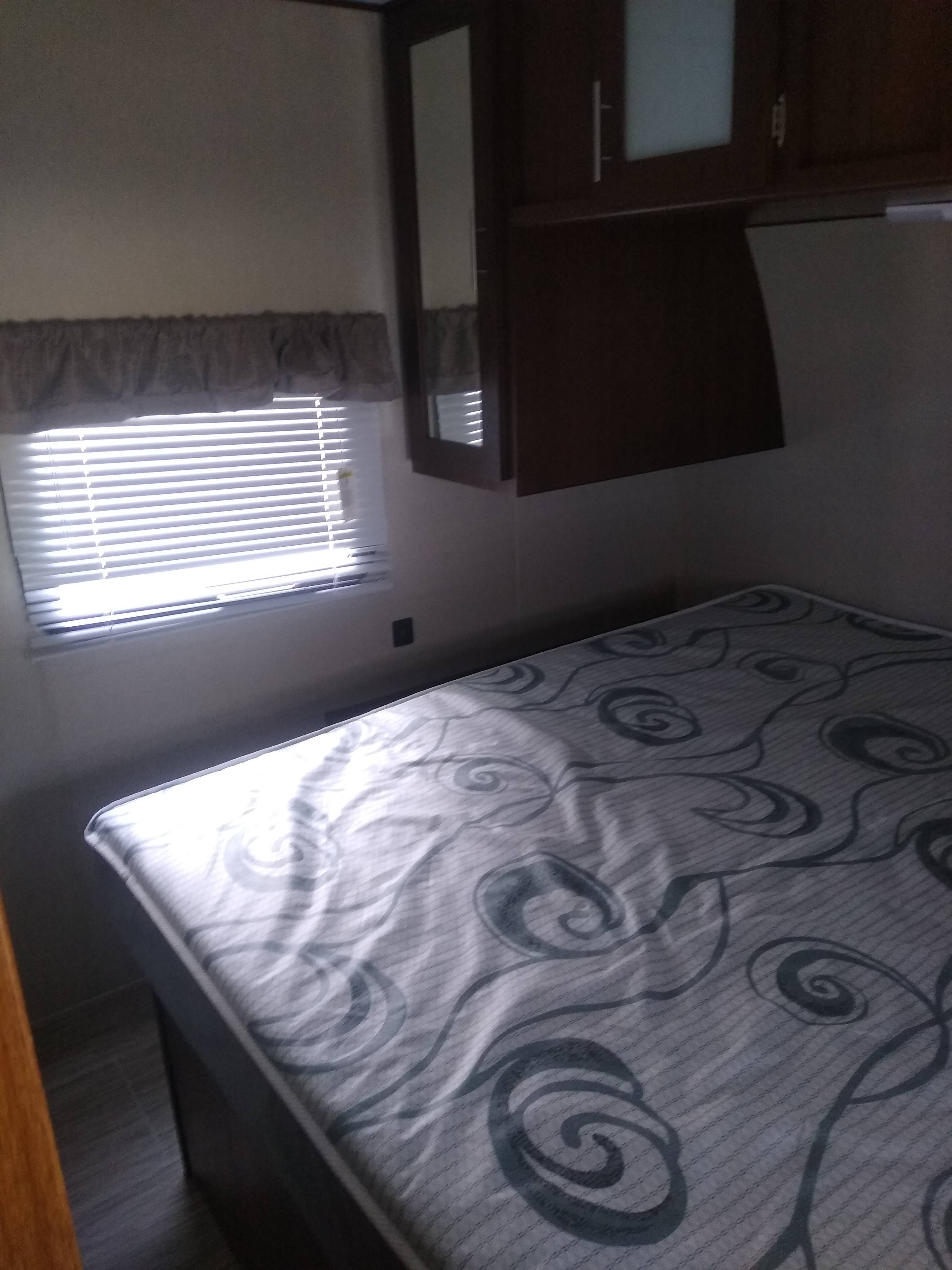 RV rental interior: cozy bedroom with window, blinds, and dark wood cabinets above a patterned mattress.. Prime Time Avenger 2020