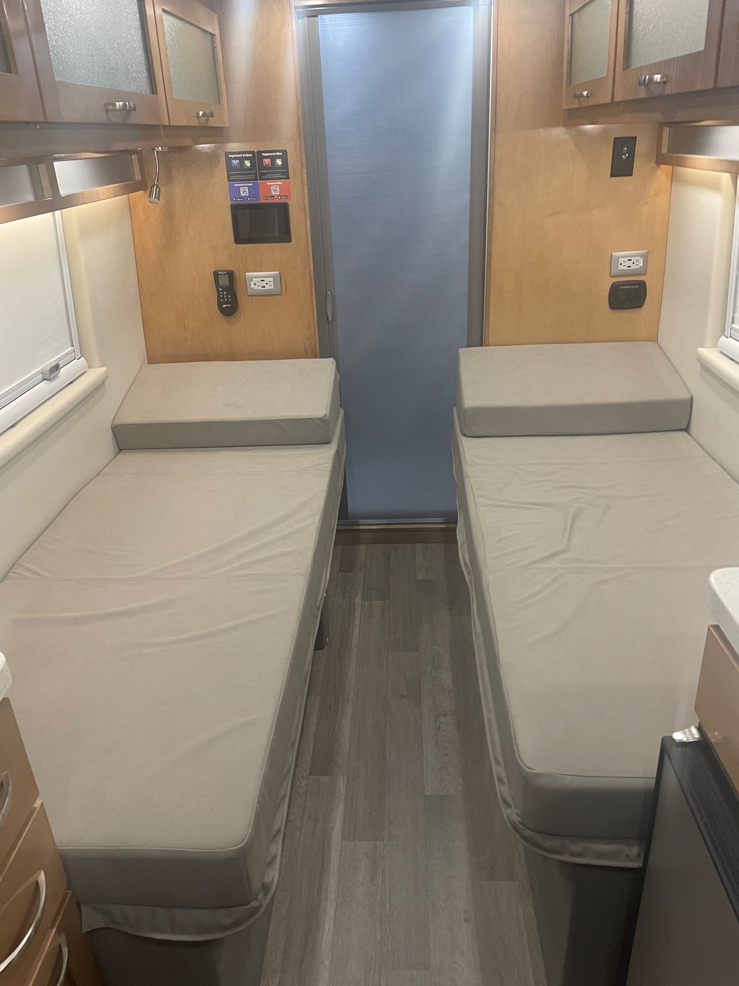 This RV rental features a cozy interior with two parallel single beds, overhead cabinets, and modern controls, perfect for compact travel.. Coachmen Nova 2021