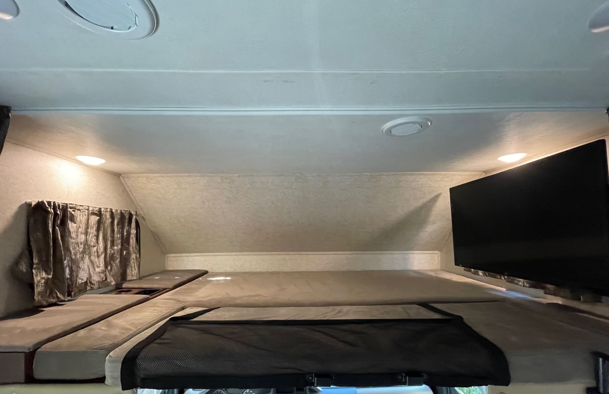 Overhead bunk in an RV rental: comfortable bed, window with curtains, ceiling vents/lights, & entertainment TV.. Forest River Forester 2018