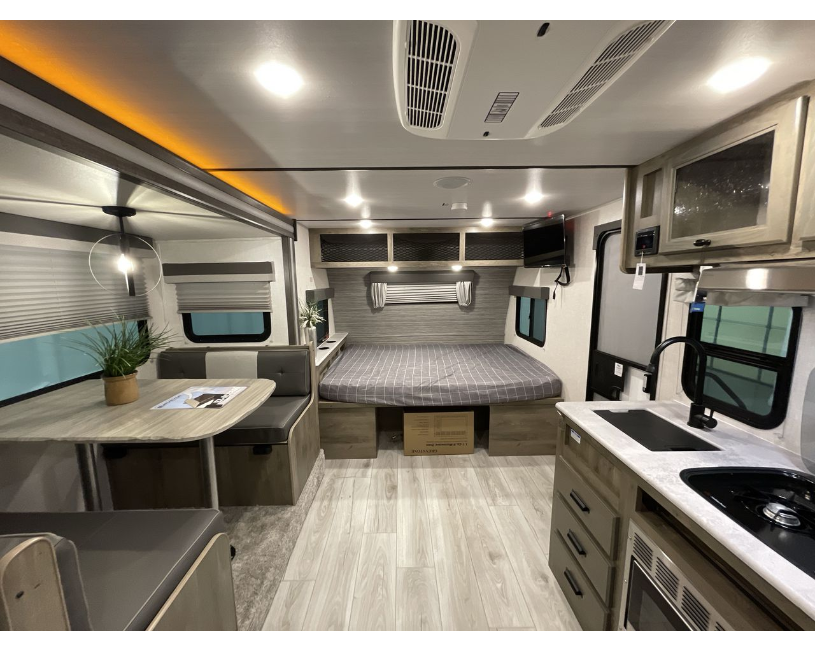 Explore this clean, modern RV rental interior showcasing a full kitchen, comfortable dining area, and cozy bedroom.. Forest River Surveyor Legend BHLE 2022