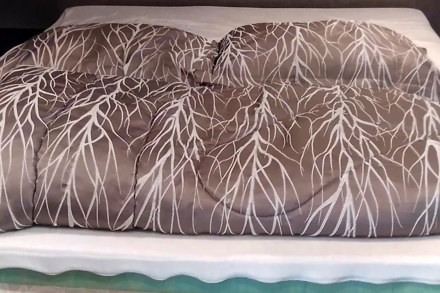 Cozy RV rental bed featuring a brown comforter with a distinctive white branch-pattern, ensuring comfort on your travels.. Jayco Jay Flight 2019