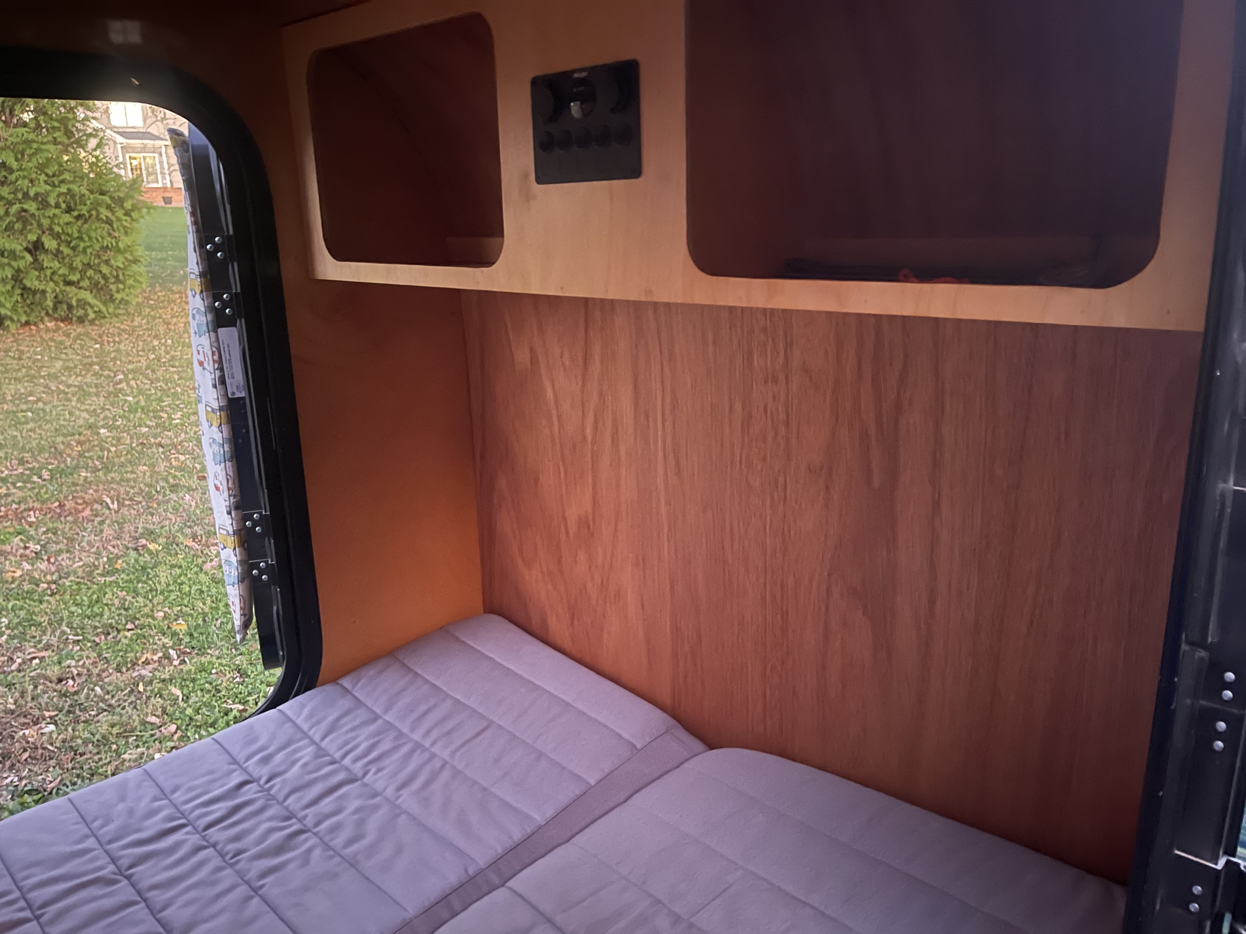 Cozy RV rental interior with a comfy bed, wooden walls, overhead storage, and an electrical panel. View outside.. Oracle Teardrops Teardrop 2020