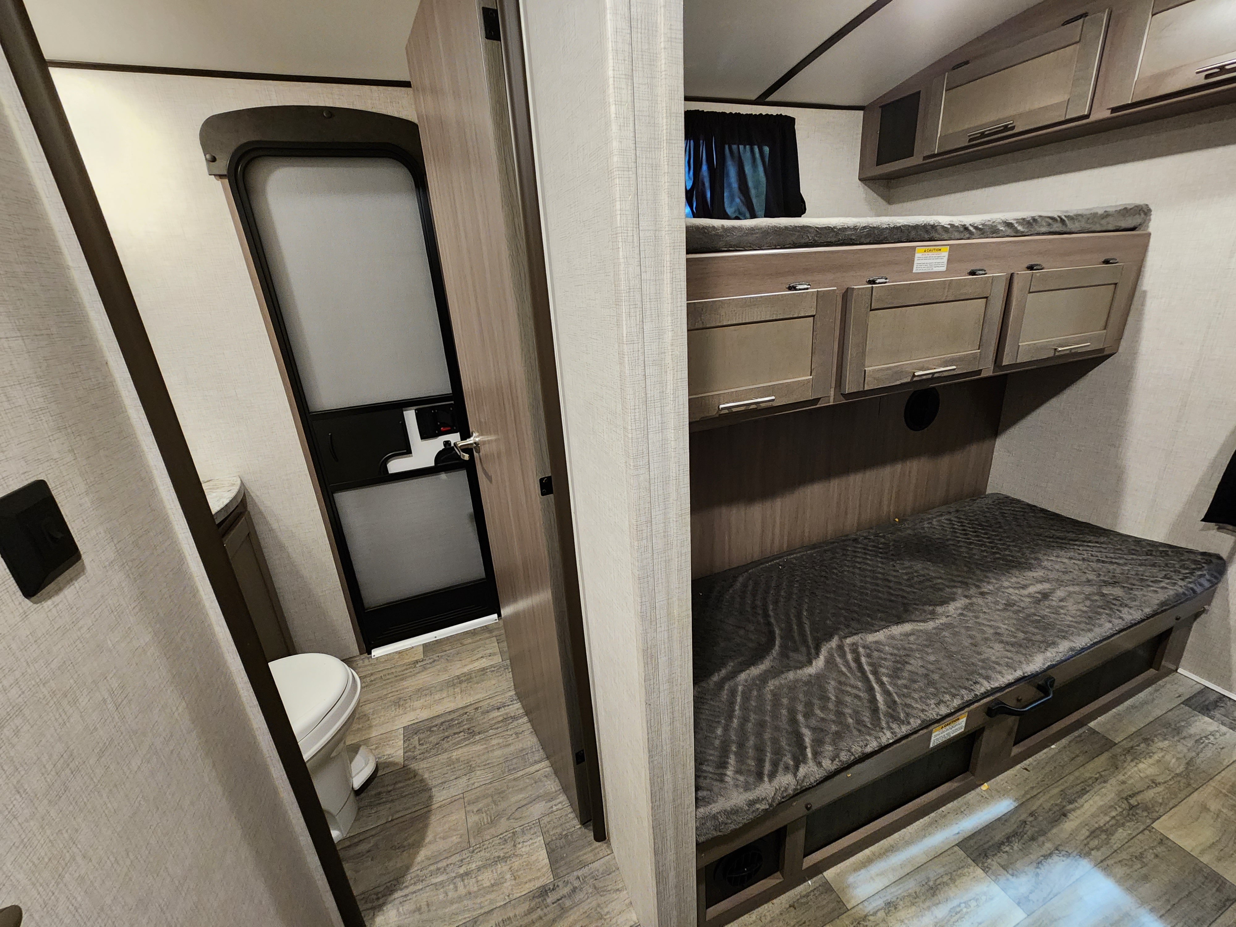 Explore this RV rental's interior: cozy bunk beds & a compact bathroom with toilet.. Crossroads Sunset Trail 2021