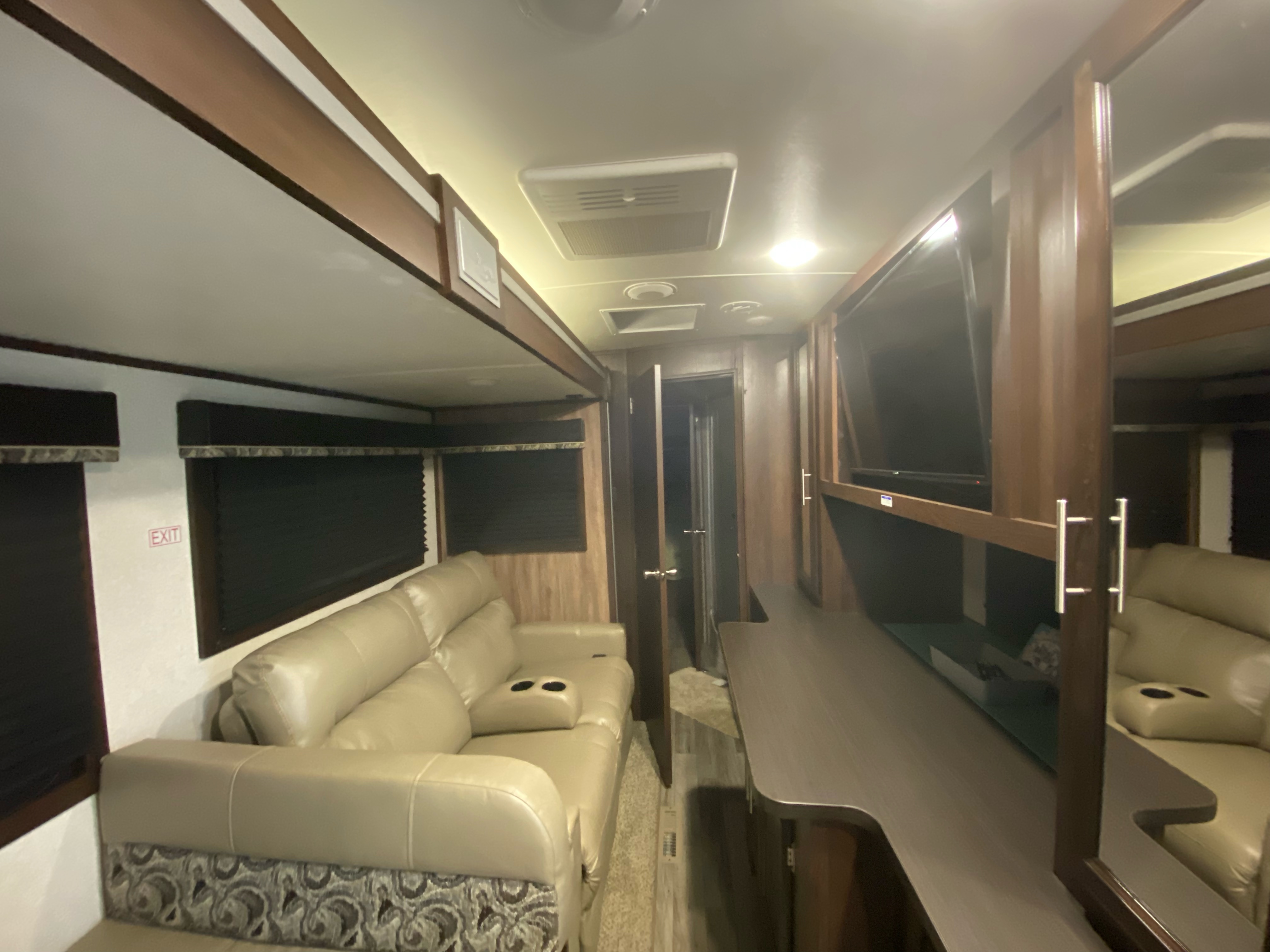 View inside an RV rental showing a light-colored couch, entertainment area with TV, and modern decor.. Jayco White Hawk 2019