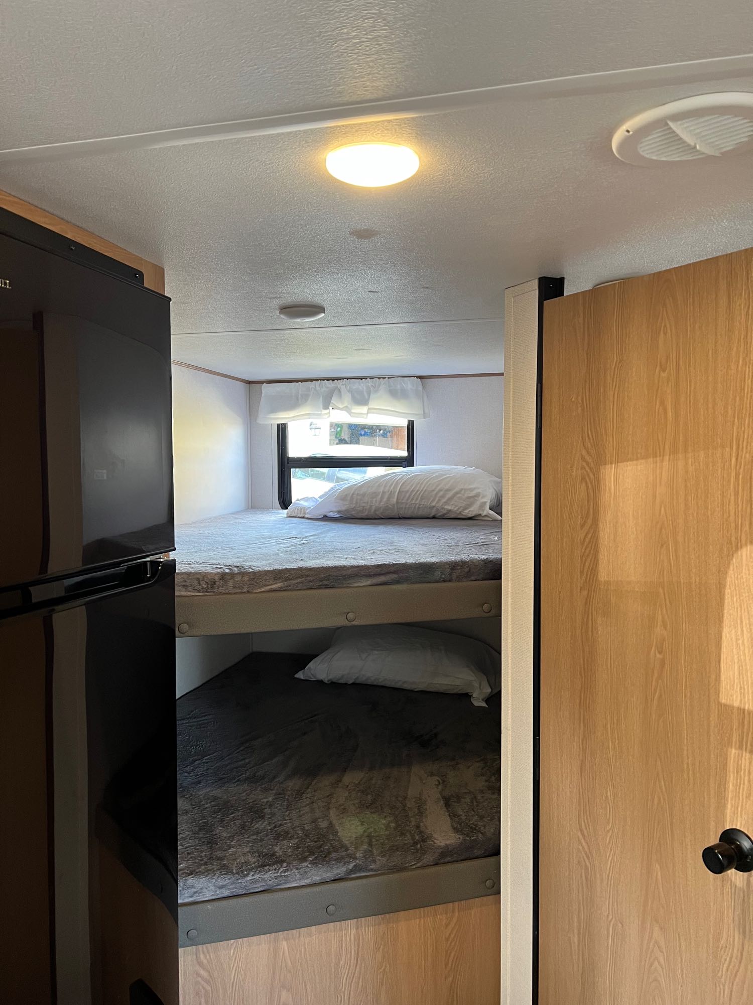 Inside an RV rental: two comfortable bunk beds, a refrigerator, and a bright, well-lit interior. Ideal for family trips.. Prime Time Avenger 2022