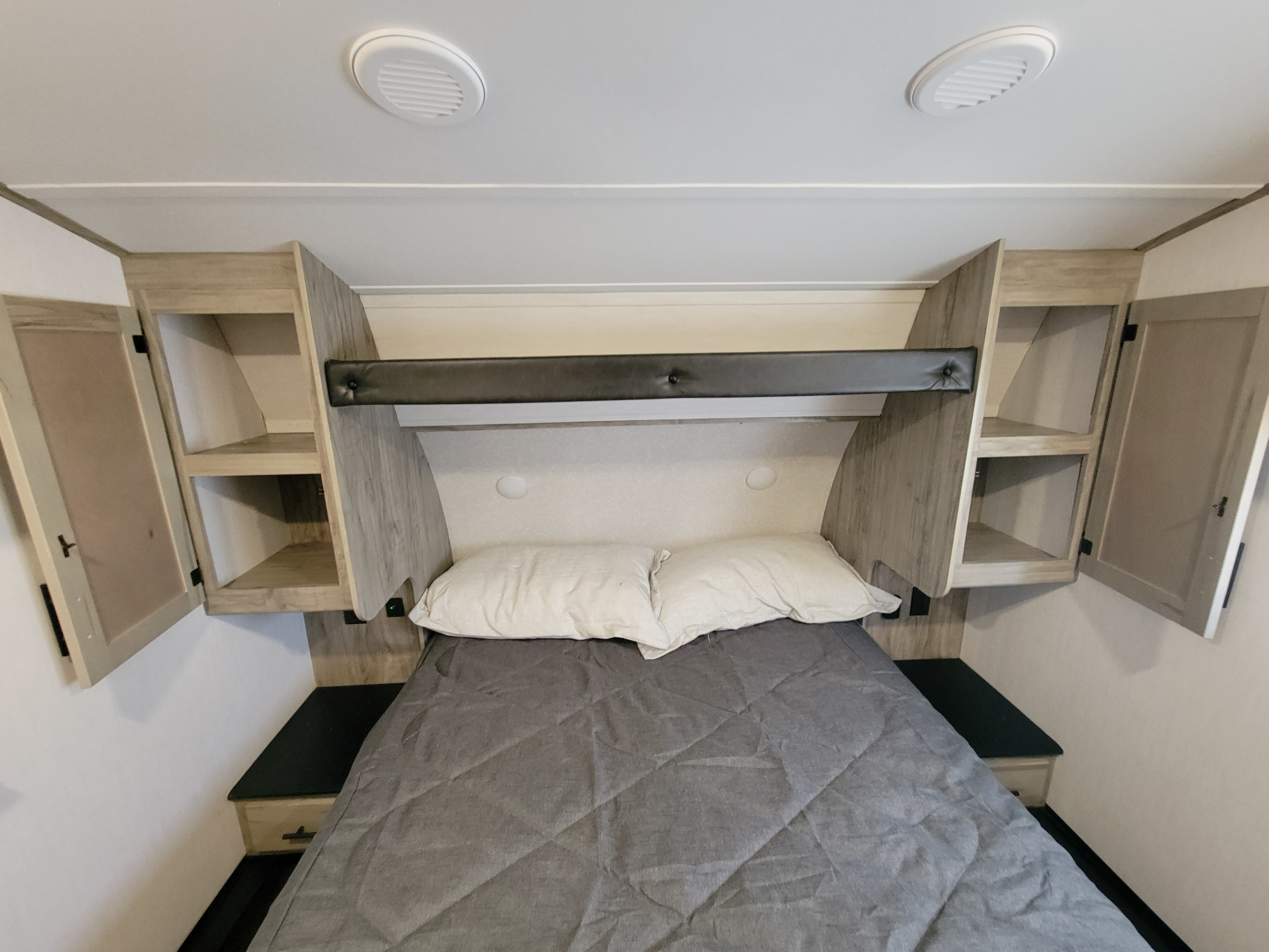 Cozy RV rental bedroom with a comfortable bed, light wood storage cabinets, and ceiling vents for a relaxing trip.. Forest River Cherokee Arctic Wolf 2022