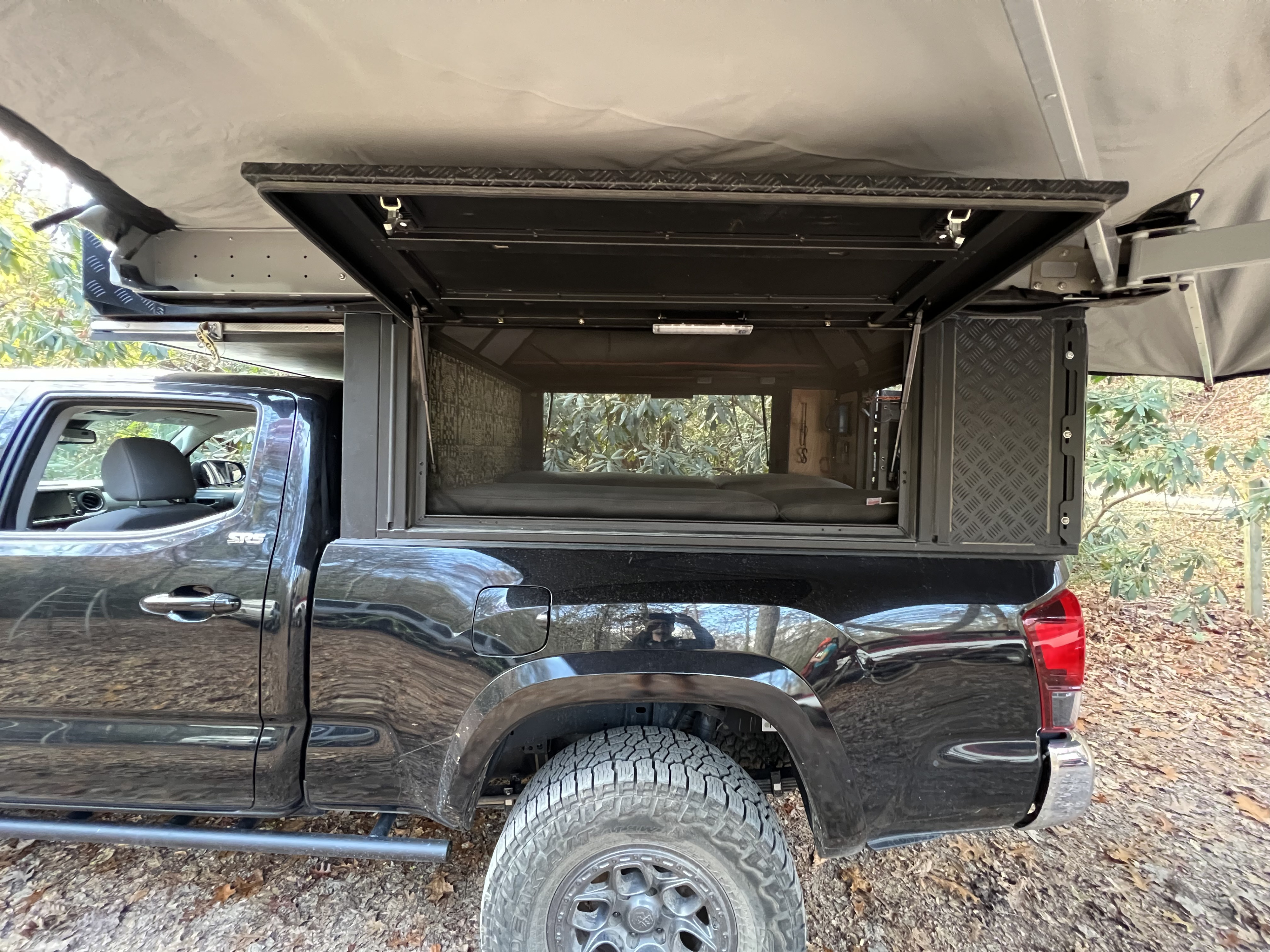 Black Tacoma truck with pop-top bed camper, ready for overland camping. An RV rental alternative for your adventure.. Toyota Tacoma 2020