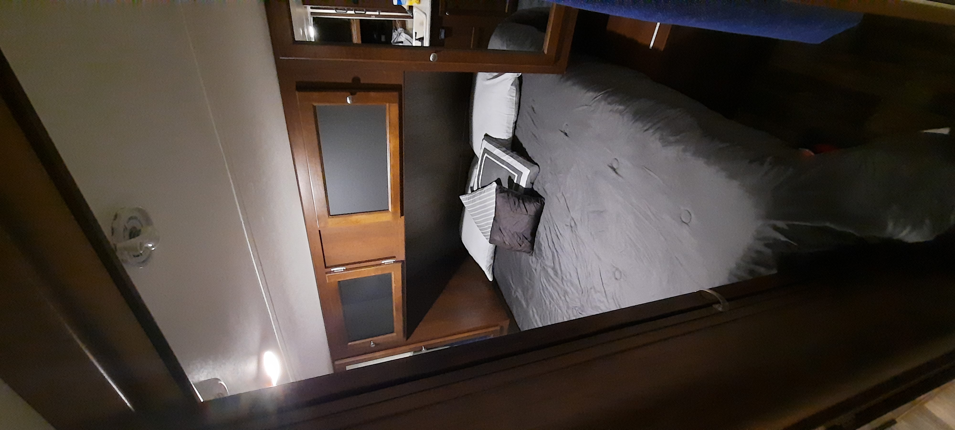 RV rental bedroom: A neatly made bed with grey bedding, accent pillows, and dark wooden built-in cabinets.. Keystone RV Bullet Ultra Lite 2016