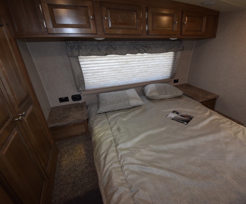 Cozy RV rental bedroom featuring a comfortable bed, overhead cabinets, and window blinds. Ideal for your next road trip!. Forest River Rockwood Ultra Lite 2019