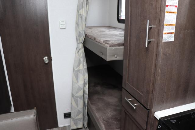 RV rental interior features bunk beds with soft padding, adjacent storage, and a glimpse of the kitchen.. Forest River Cruise Lite 2019