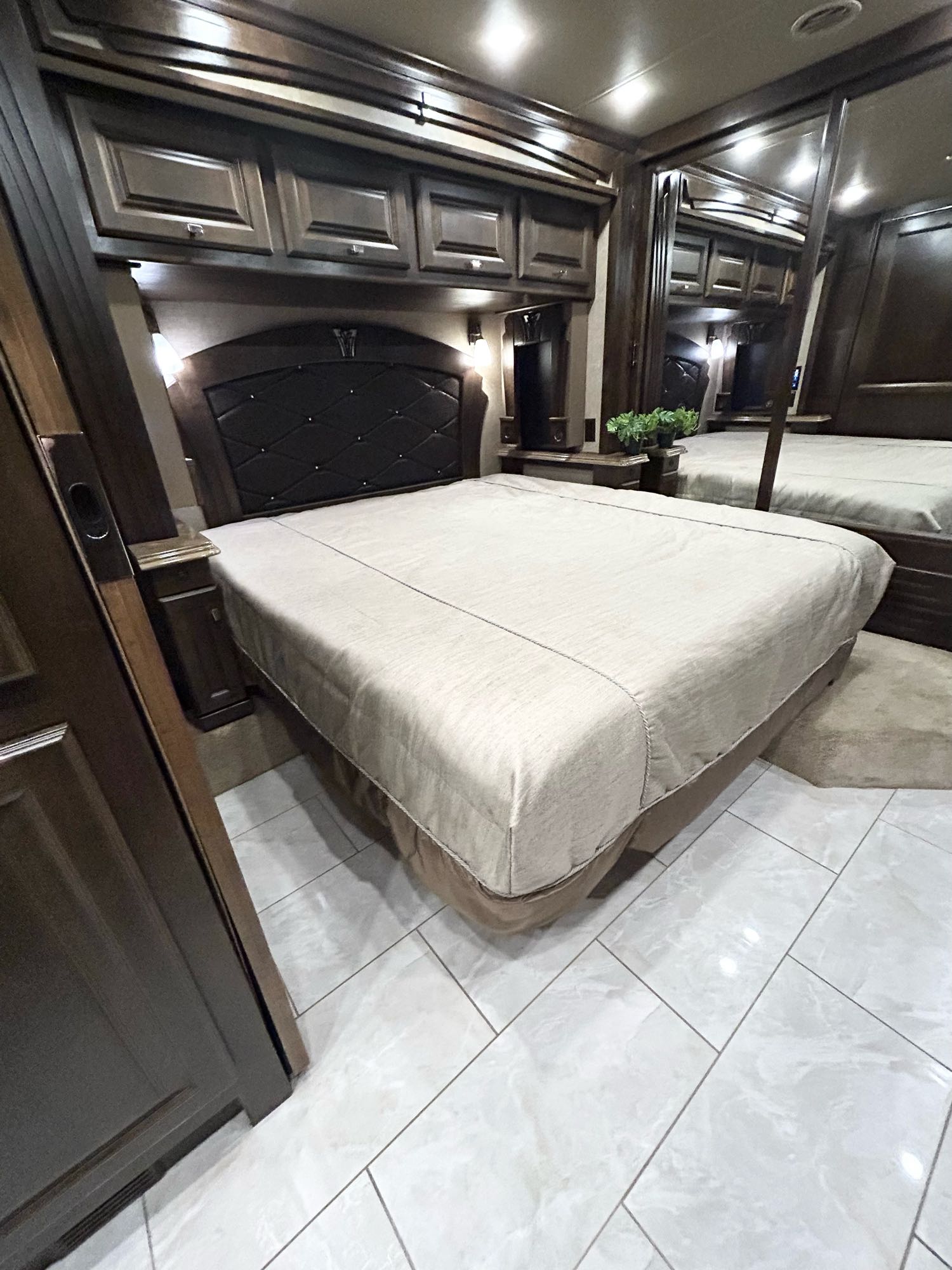 Comfortable RV rental bedroom with dark wood cabinetry, plush bed, and modern tiled flooring.. Phaeton Phaeton Motorhome 2017