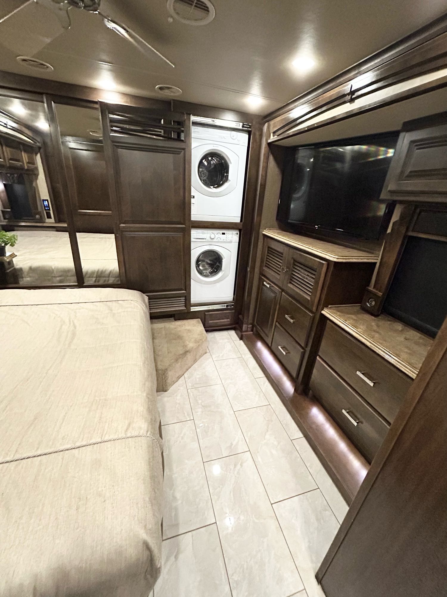 Modern RV rental bedroom setup with stacked washer/dryer, flat-screen TV, and mirrored closets.. Phaeton Phaeton Motorhome 2017