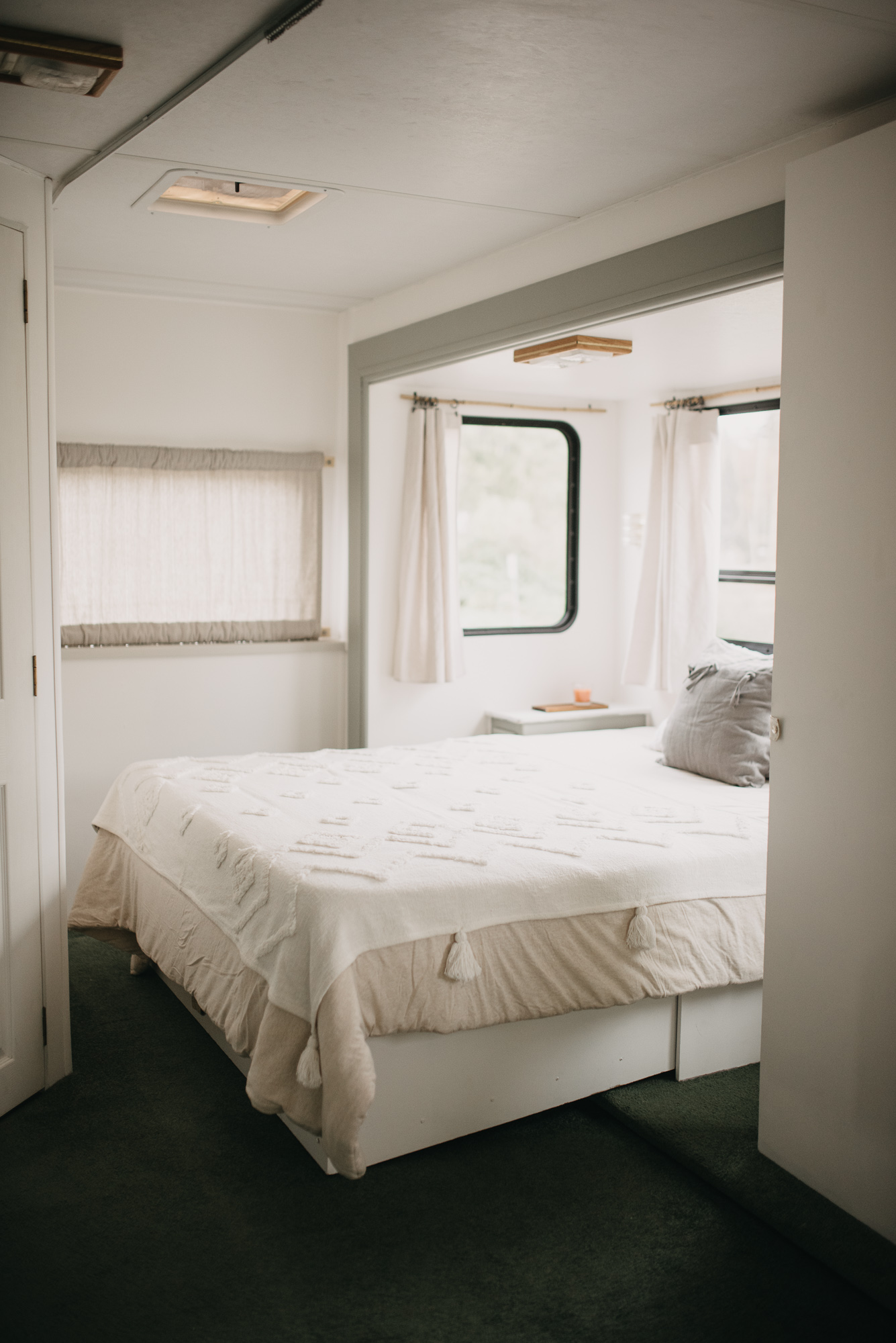 Cozy, bright bedroom in an RV rental, featuring a white bed, green carpet, and large windows with natural light.. Glendale Royal Classic 1999