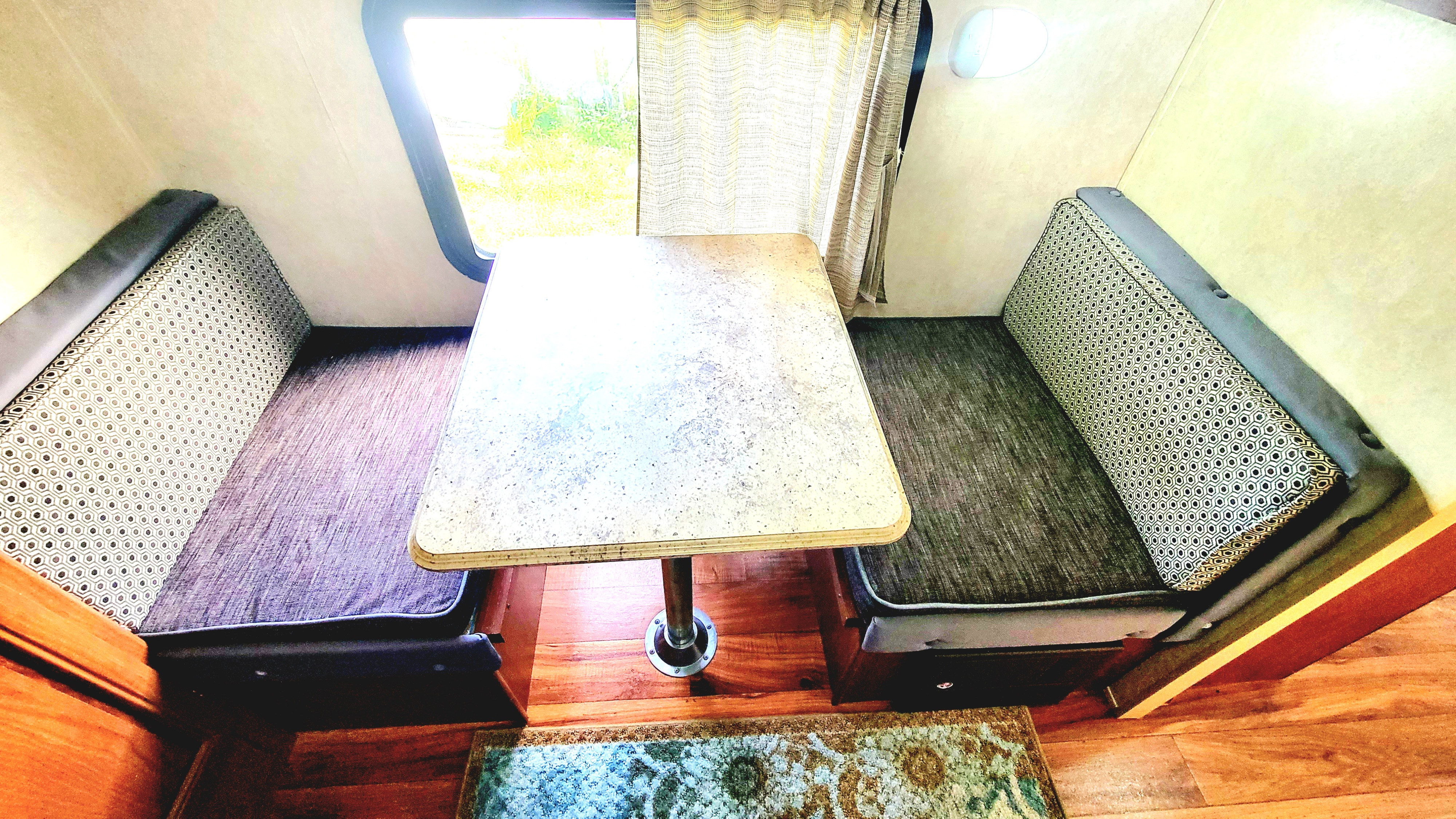 RV rental dinette: patterned booth seating, central table, and window offer a cozy dining space for travel.. Forest River Salem 2016