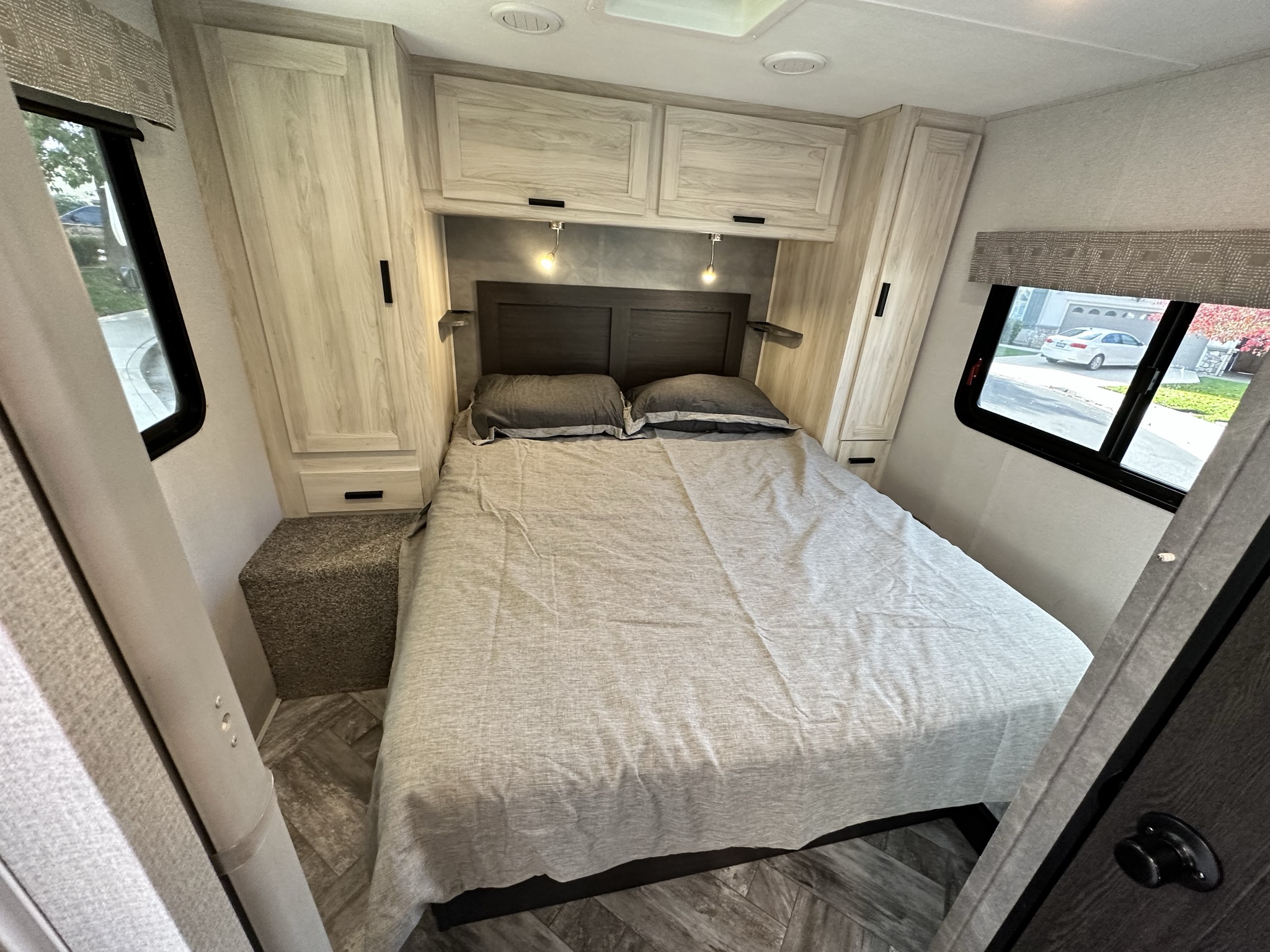 Cozy, modern RV rental bedroom with a comfy bed, overhead cabinets, and windows. Perfect for travel comfort.. Coachmen Sunseeker 2022