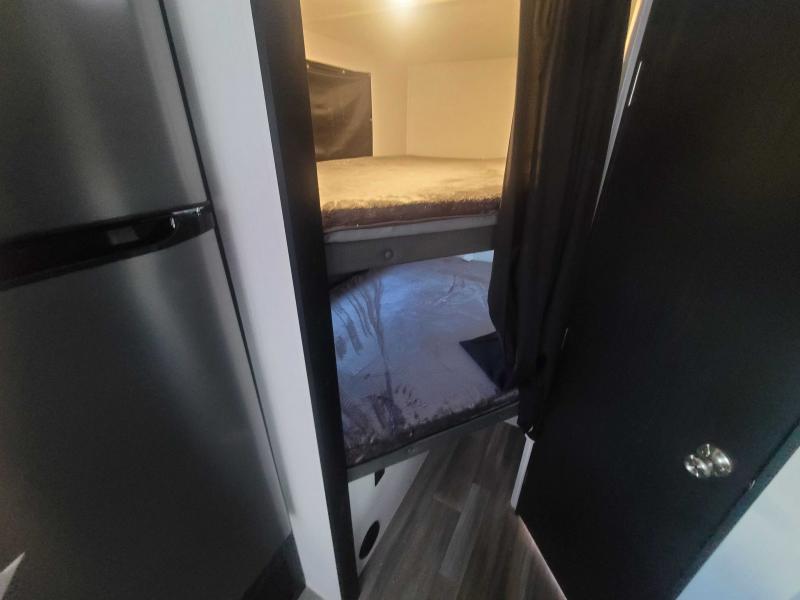 Compact RV rental interior featuring comfortable bunk beds with privacy curtains and a refrigerator. Ideal for family travel.. Coachmen 257BHS 2022