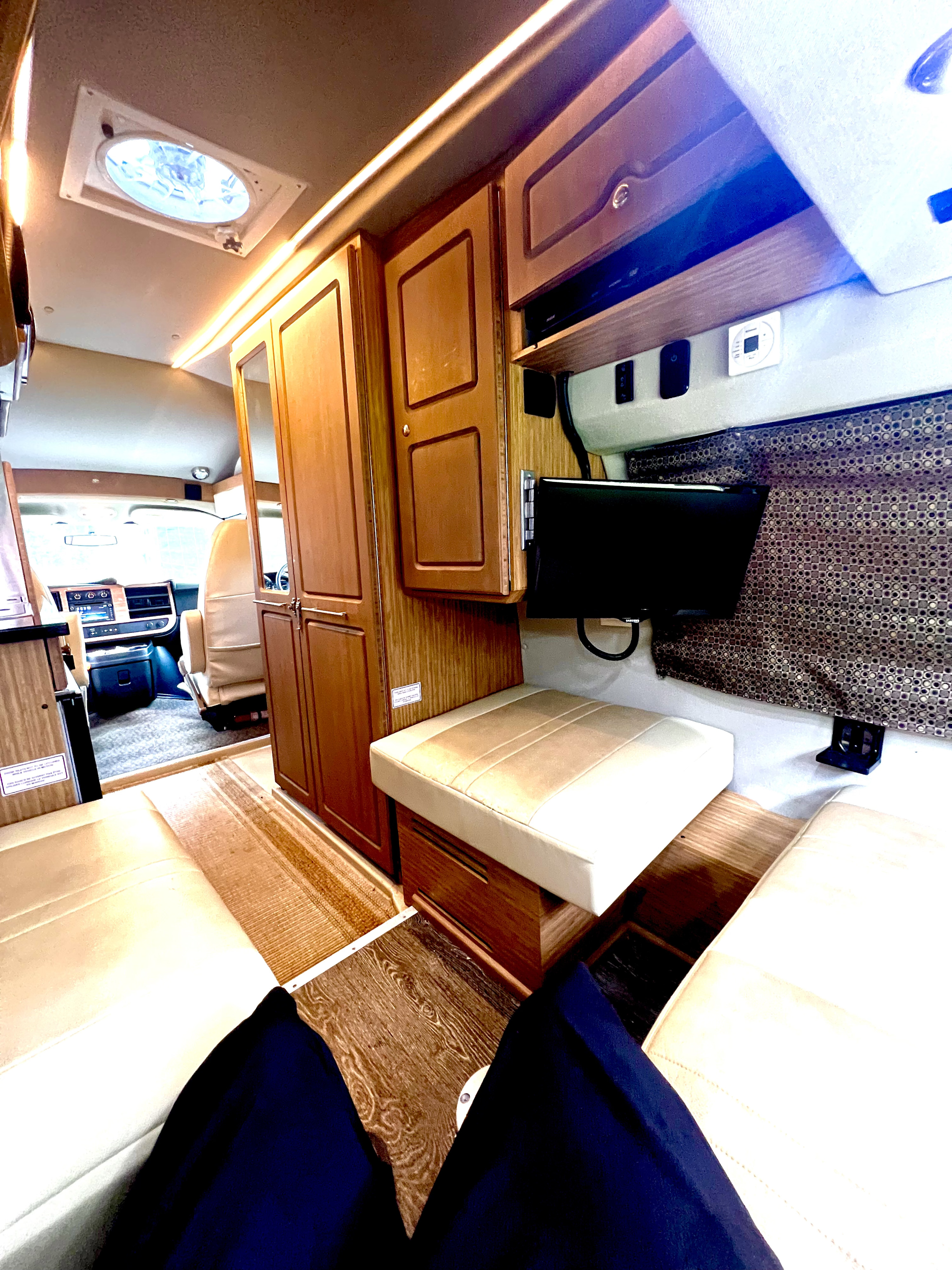Inside a comfy RV rental: living area with TV, cabinets, and a view into the cockpit. Ideal for road trips.. Roadtrek Roadtrek Class B 2015