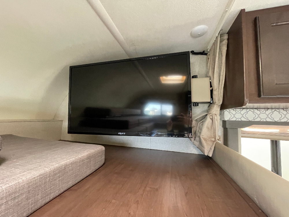 This RV rental offers a cozy interior with a mounted TV, comfortable bed cushions, and storage, designed for road trip comfort.. Thor Freedom Elite 2019
