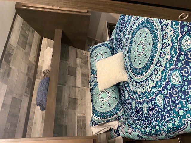 RV rental bedroom featuring vibrant blue and teal mandala bedding, rustic wood paneling, and cozy setup for travel.. Keystone RV CMMM262BH21 2021