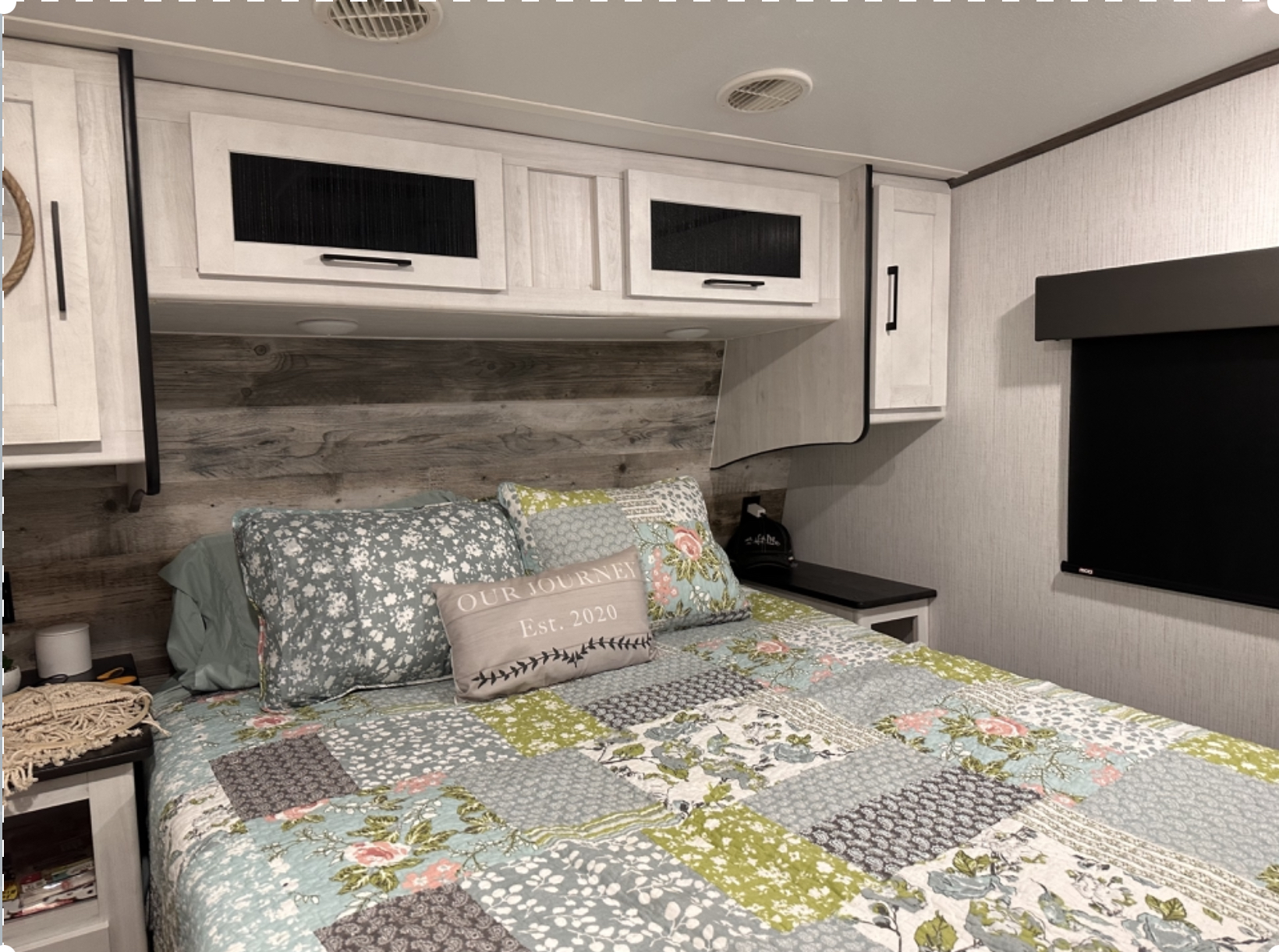 Relaxing RV rental bedroom featuring a patchwork quilt, ample storage cabinets, and wall-mounted TV for comfort.. Heartland RVs Milestone 2022