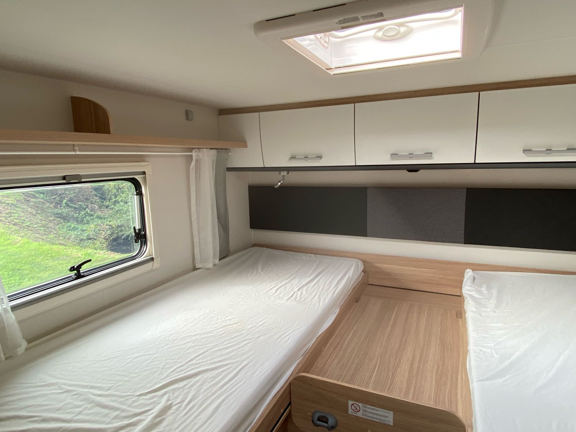 RV rental interior: Clean sleeping area with two single beds, overhead cabinets, and a skylight.. Sunlight 2024