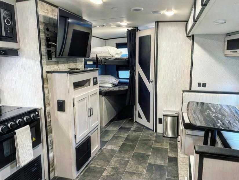 Explore this RV rental's modern interior: full kitchen, dinette, wall TV, and cozy bunk beds.. Heartland Other 2022