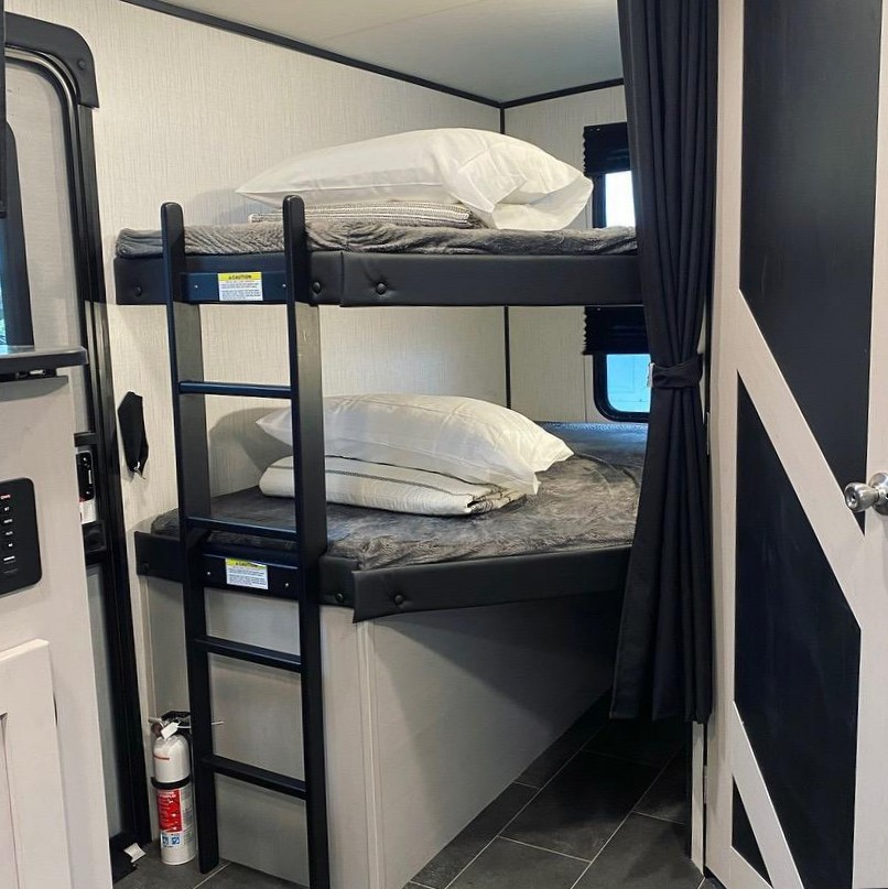 Cozy RV rental interior: two bunks with bedding, a ladder, and a fire extinguisher below. Ideal for family road trips.. Heartland Other 2022