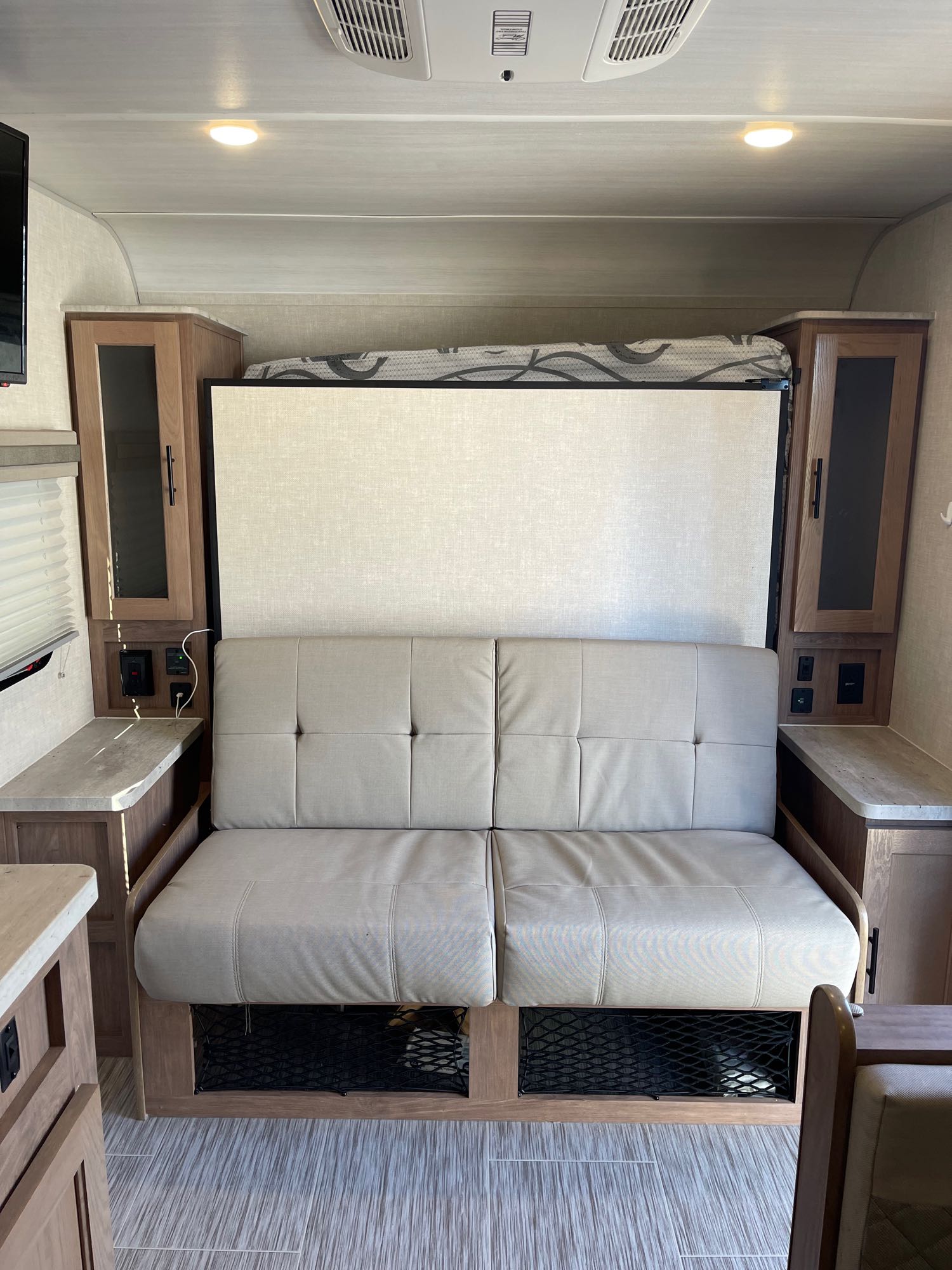 RV rental interior showing a comfortable sofa that converts to a bed, surrounded by practical storage and charging ports.. Forest River No Boundaries 19.3 2021