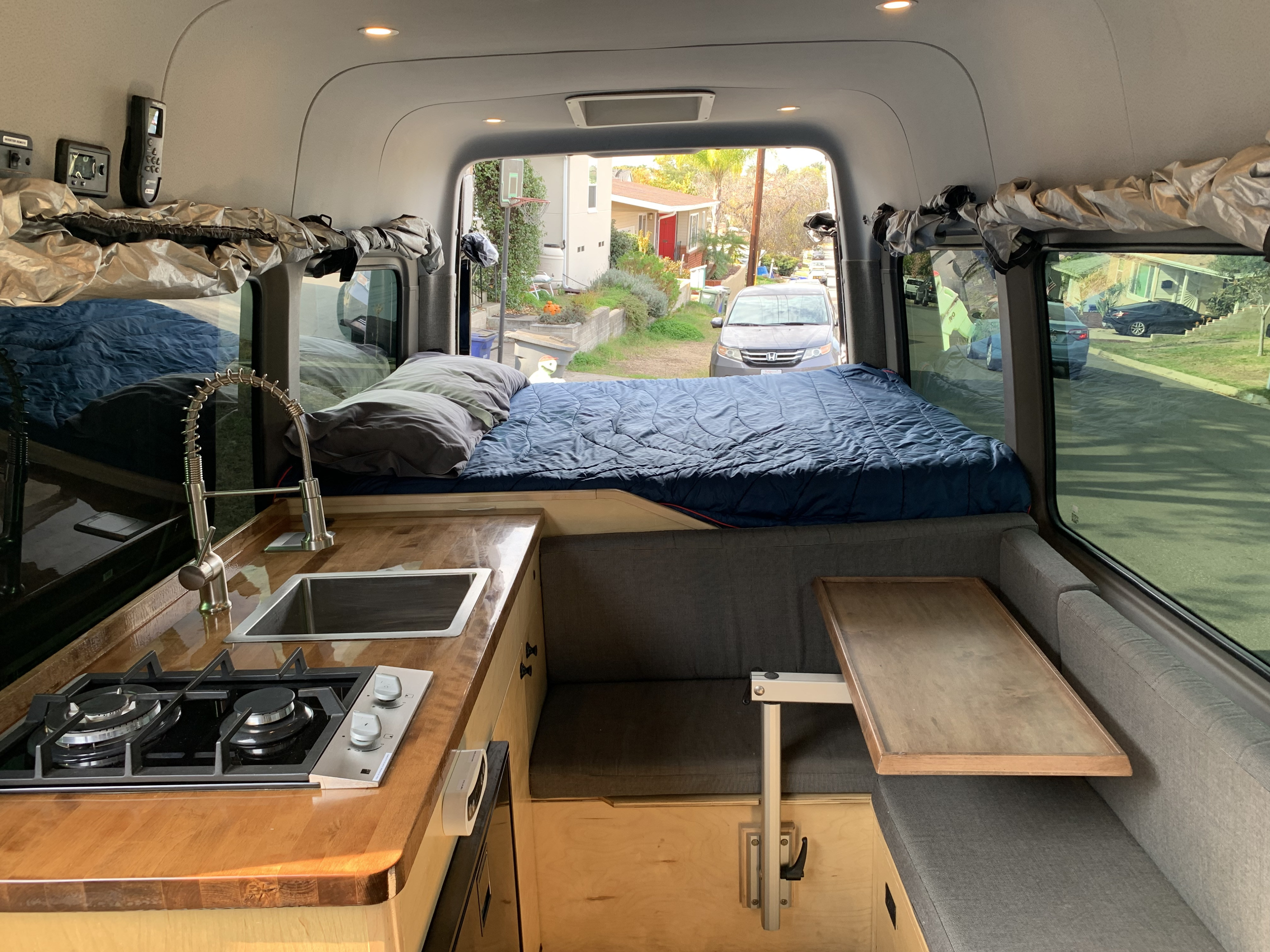 Cozy RV rental interior featuring a comfortable bed, compact kitchen, and adaptable dining table for adventurers.. Mercedes-Benz Sprinter 2018