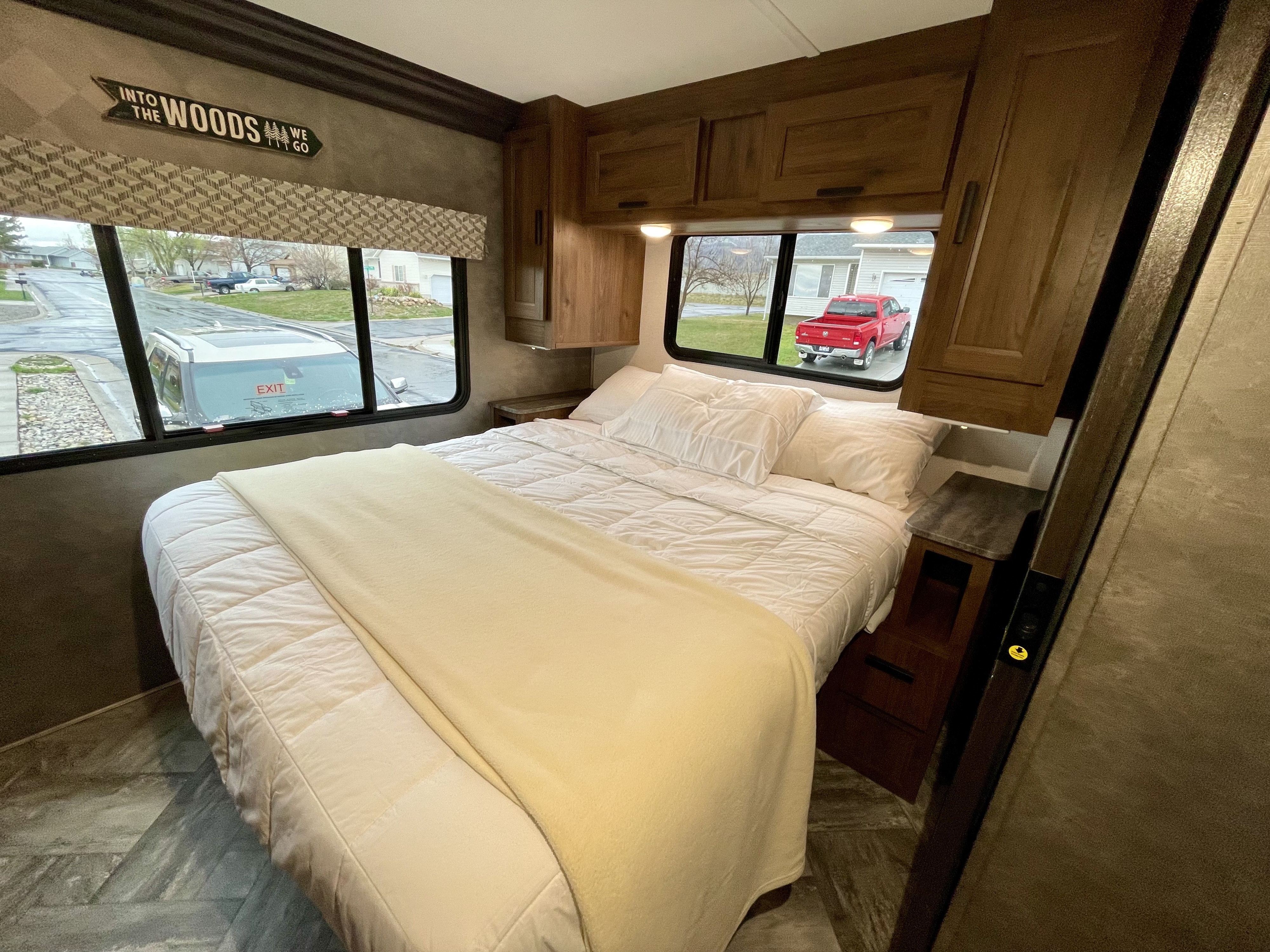 Inside an RV rental: a cozy bedroom with a clean bed, wooden cabinets, and large windows.. Forest River Forester 2022