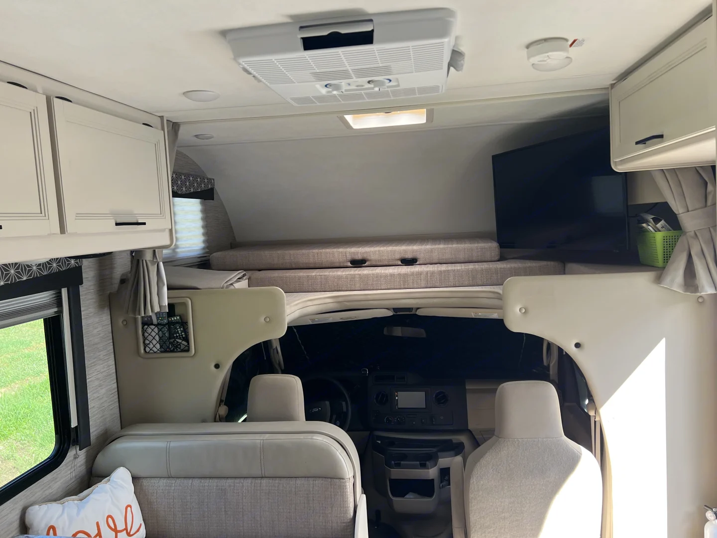 Spacious RV rental interior featuring a bunk over cab, TV, overhead cabinets, and dinette seating. Perfect for adventure!. Thor Freedom Elite 2022