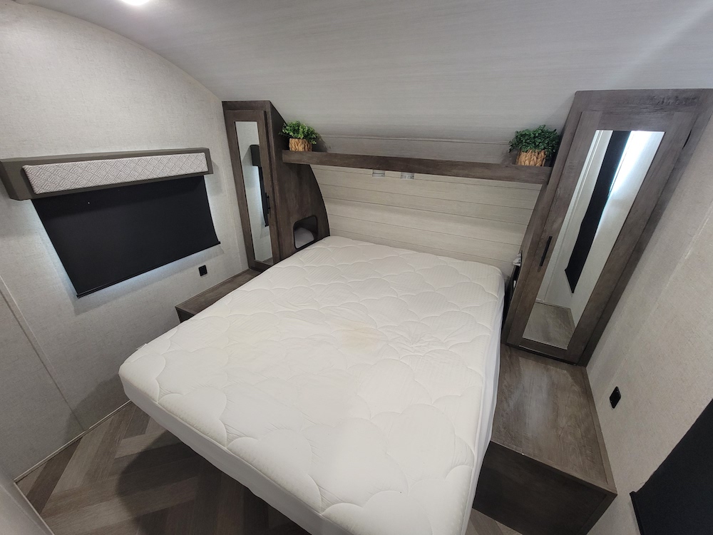 Comfortable RV rental bedroom with a queen bed, built-in storage, window, and mirrored wardrobe for your trip.. Forest River Salem Cruise Lite 2020