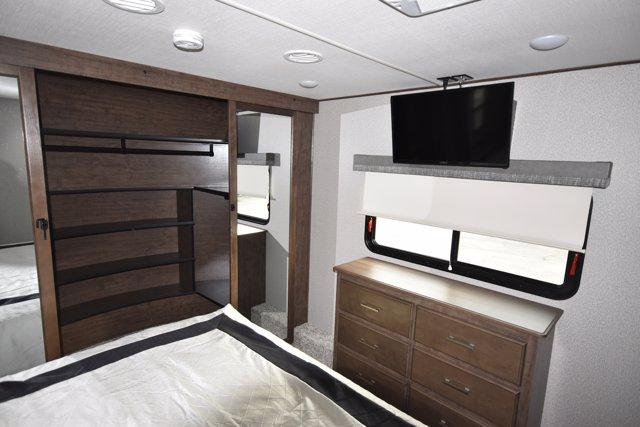 Spacious RV rental bedroom featuring a large built-in closet, dresser, windows with blinds, TV, and comfortable bed.. Grand Design Solitude 2020